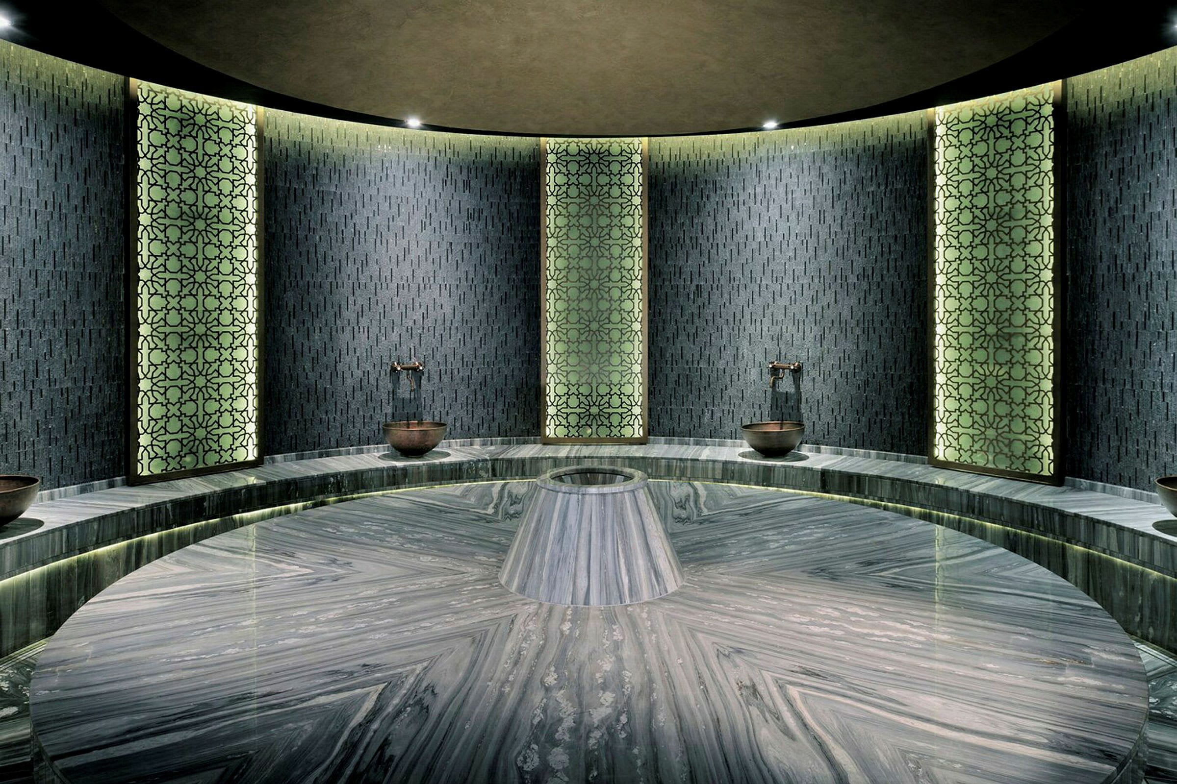 Modernisti suunniteltu hamam, jossa on kuvioidut seinäpaneelit ja keskellä pyöreä marmorilava. (Tekoälyn luoma teksti)