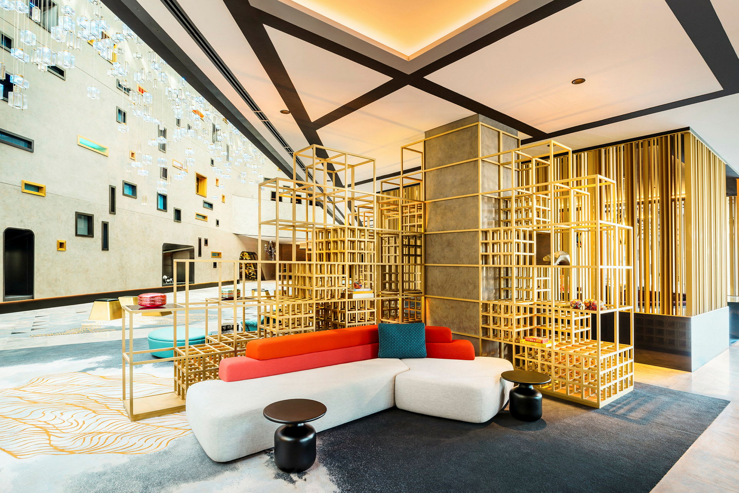 Moderni hotelliaula, jossa on geometrisia koristeita ja värikkäitä huonekaluja. (Tekoälyn luoma teksti)