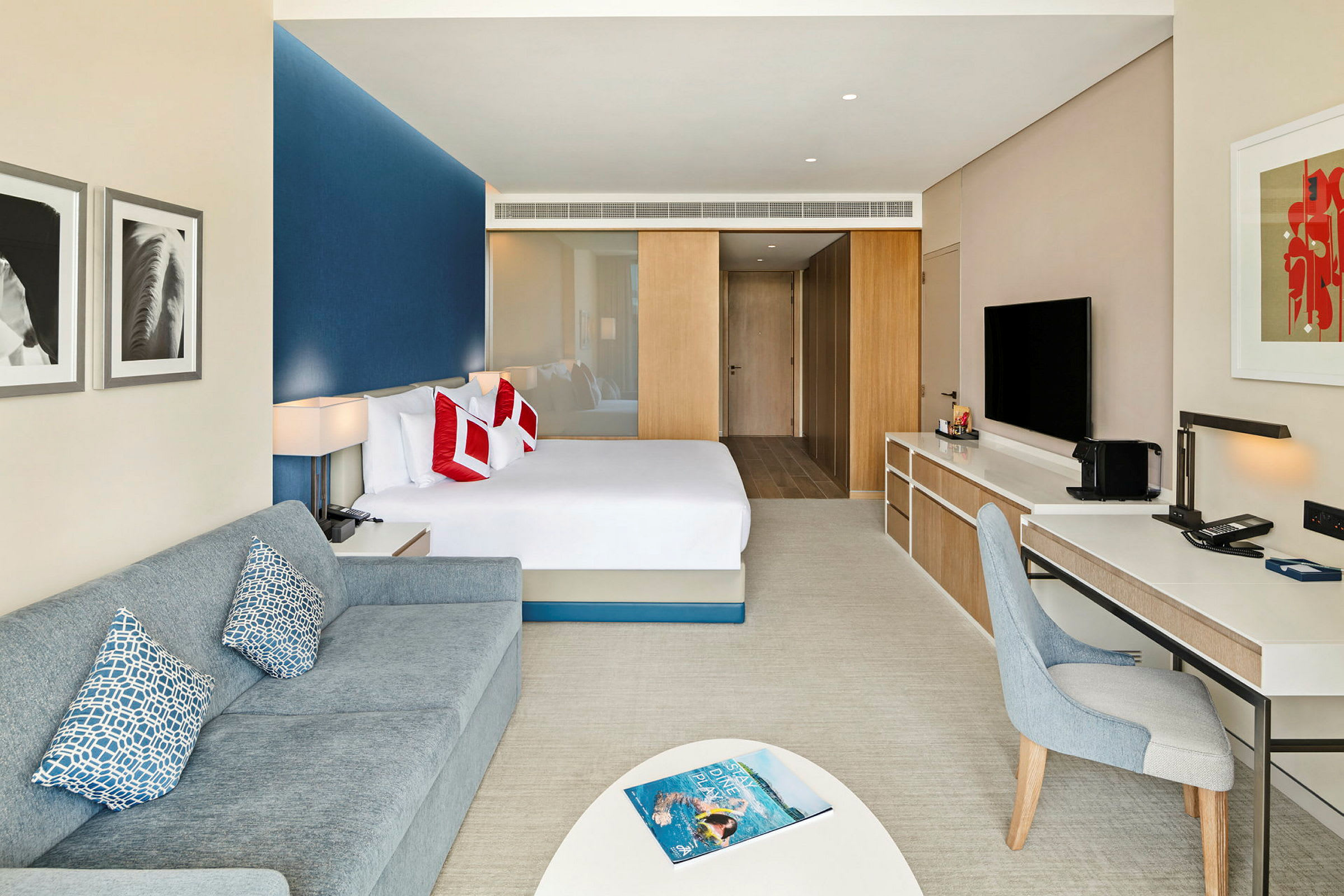 Moderni hotellihuone, jossa sänky, sohva ja työpöytä. (Tekoälyn luoma teksti)