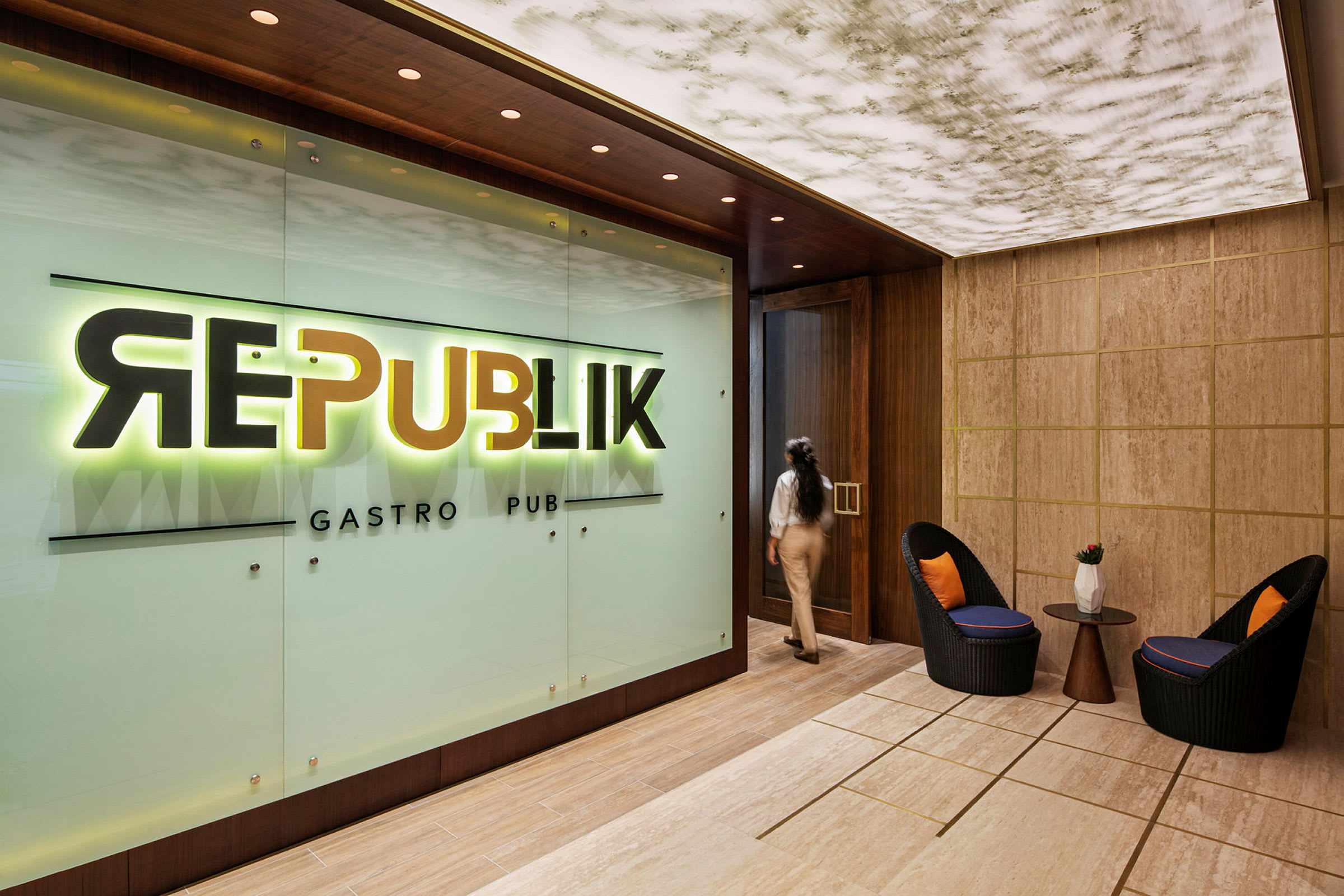 Ravintolan tai baarin sisäänkäynti, jossa on kyltti "Republik Gastro Pub". Etualalla näkyy kaksi tuolia ja pöytä. (Tekoälyn luoma teksti)