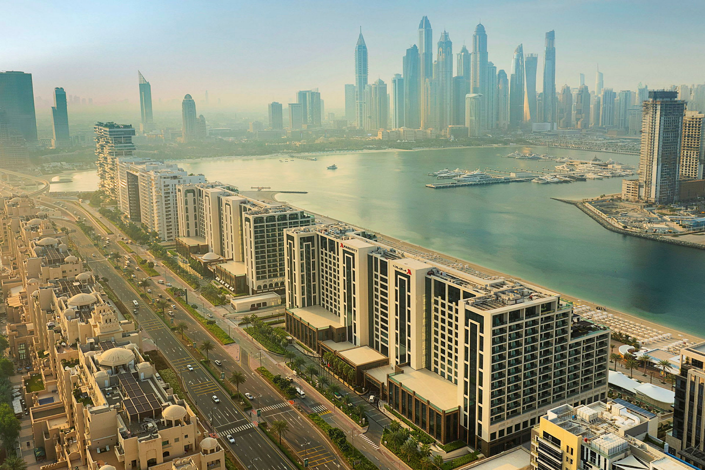 Ilmava näkymä Dubain Marinaan, jossa moderneja korkeita rakennuksia, asuinalueita ja venesatama veden äärellä. (Tekoälyn luoma teksti)