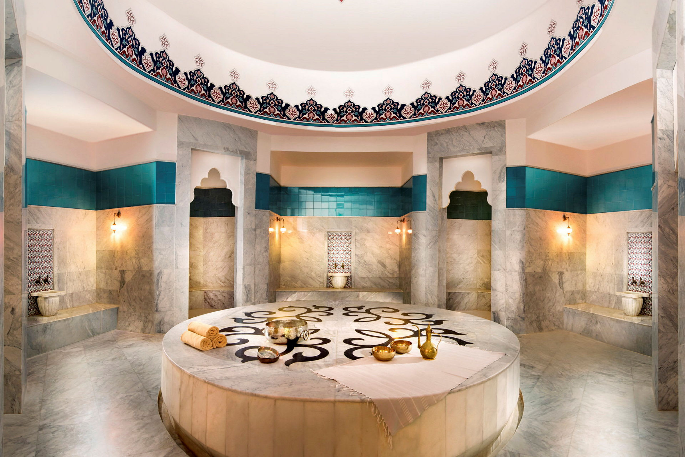 Hamam-huone, jossa on marmoria, turkooseja yksityiskohtia ja koristeluita. (Tekoälyn luoma teksti)