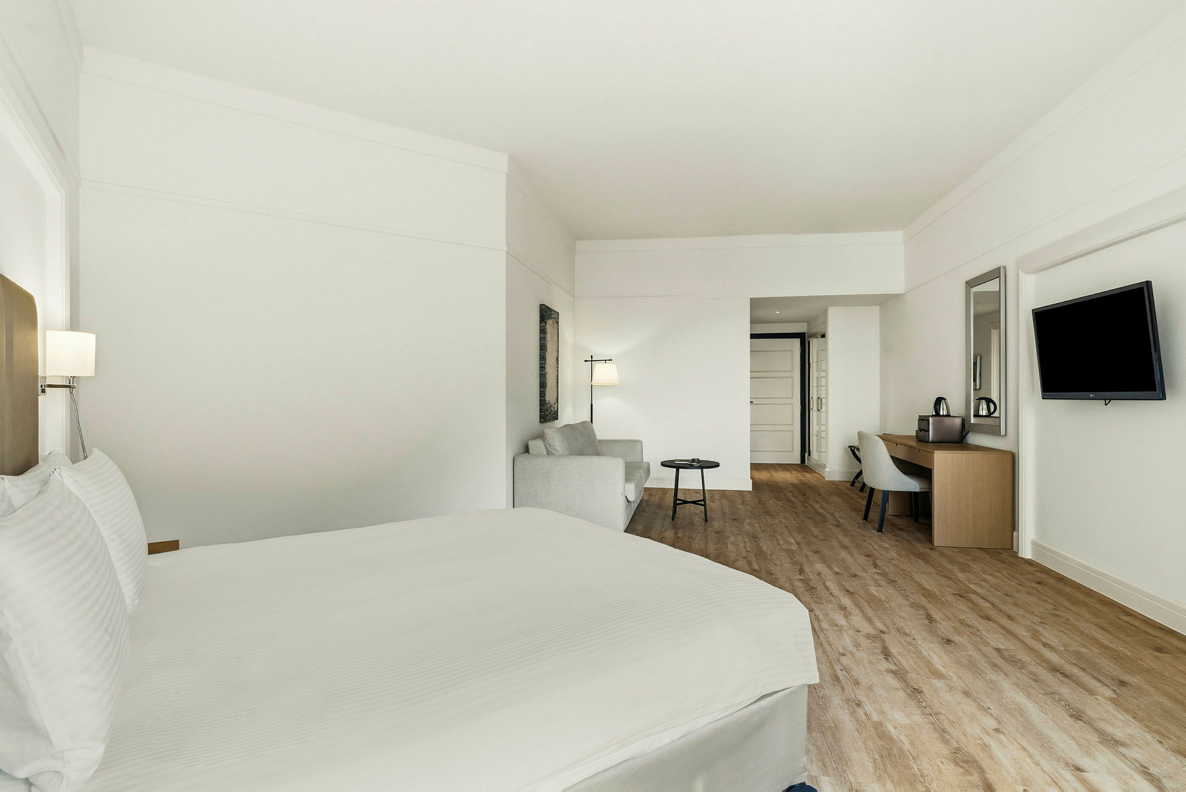Hotellihuone, jossa on sänky, istuinryhmä ja kirjoituspöytä. (Tekoälyn luoma teksti)