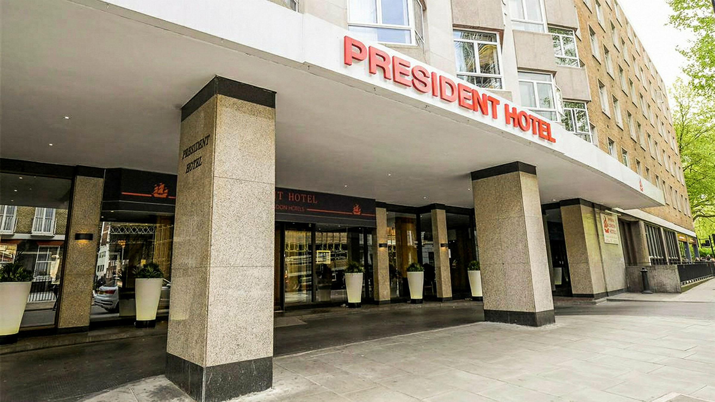 President-hotellin etusivu sisäänkäynnillä ja kyltillä. (Tekoälyn luoma teksti)