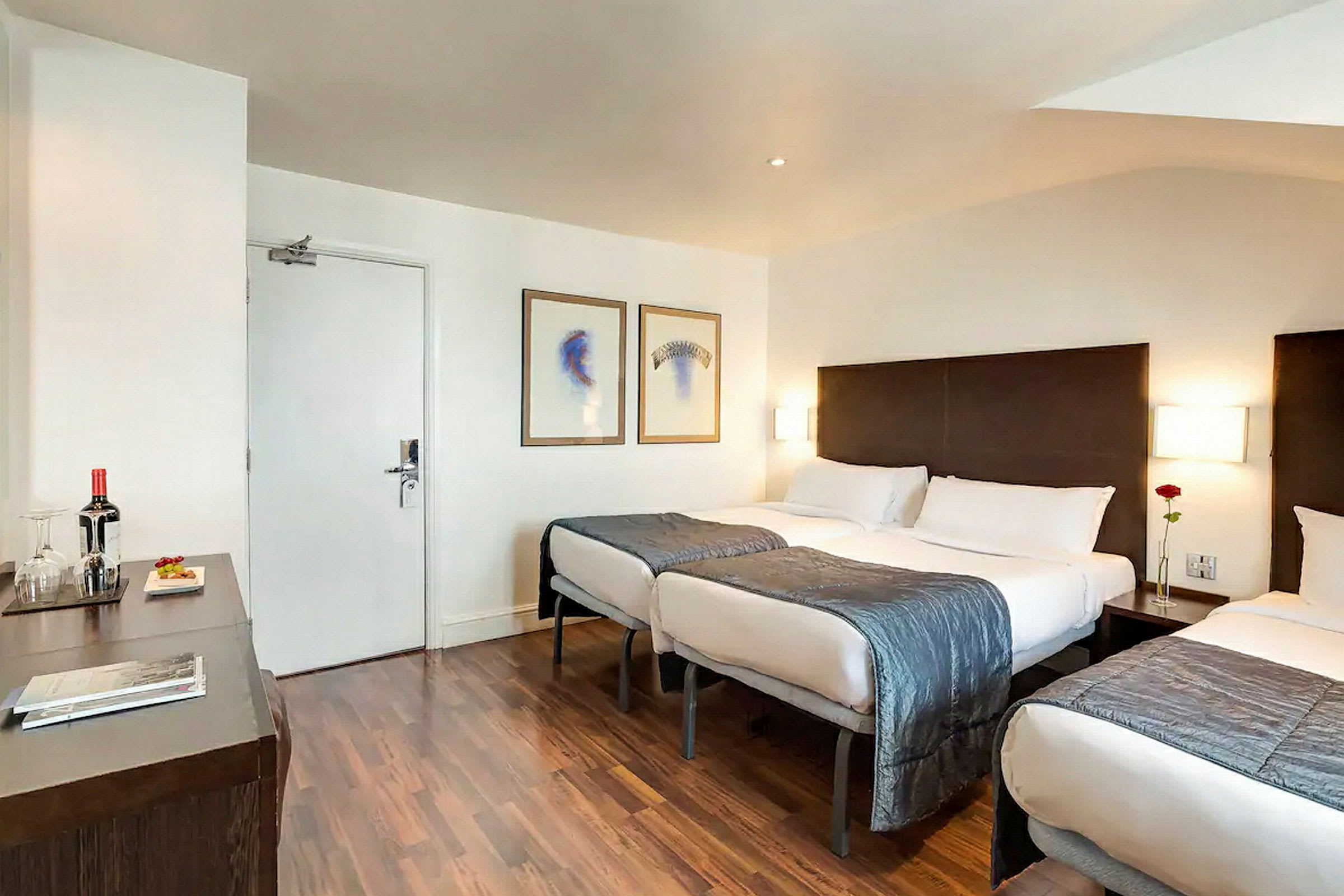 Hotellihuone, jossa on kolme sänkyä ja moderni sisustus. (Tekoälyn luoma teksti)
