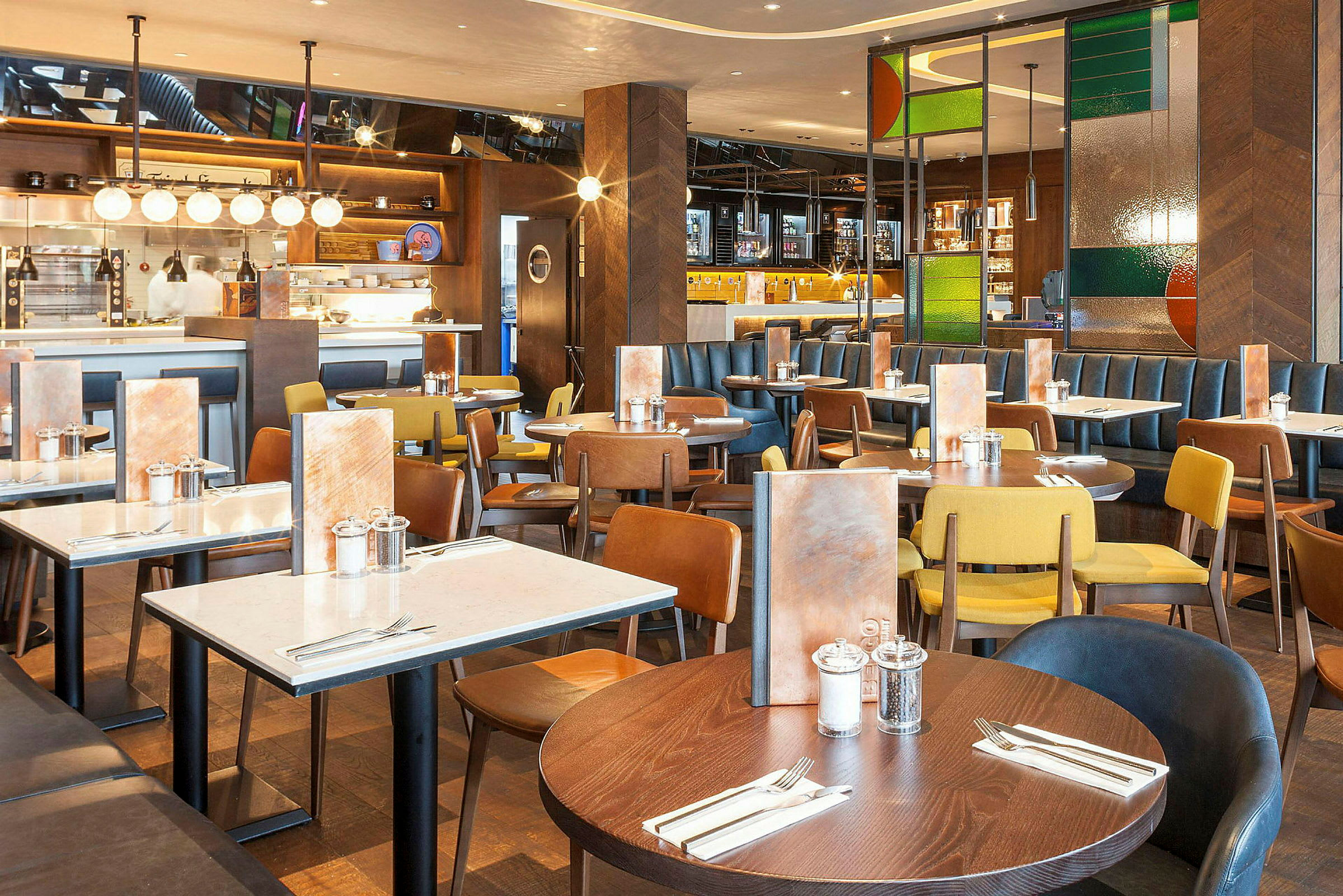 Ravintola, jossa on useita ruokapöytiä ja erivärisiä tuoleja. (Tekoälyn luoma teksti)