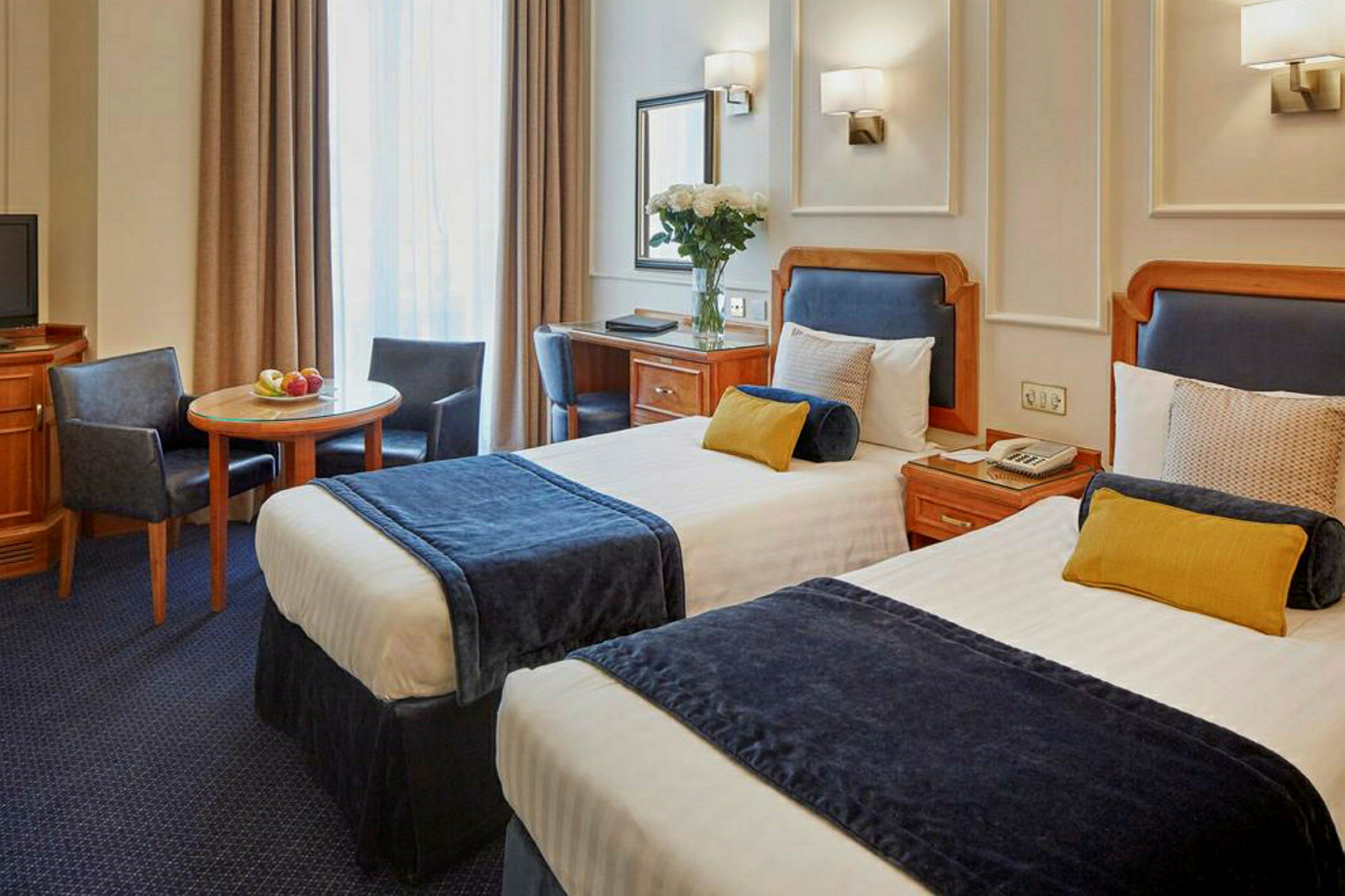 Hotellihuone, jossa kaksi erillistä vuodetta, pöytä ja tuolit. (Tekoälyn luoma teksti)