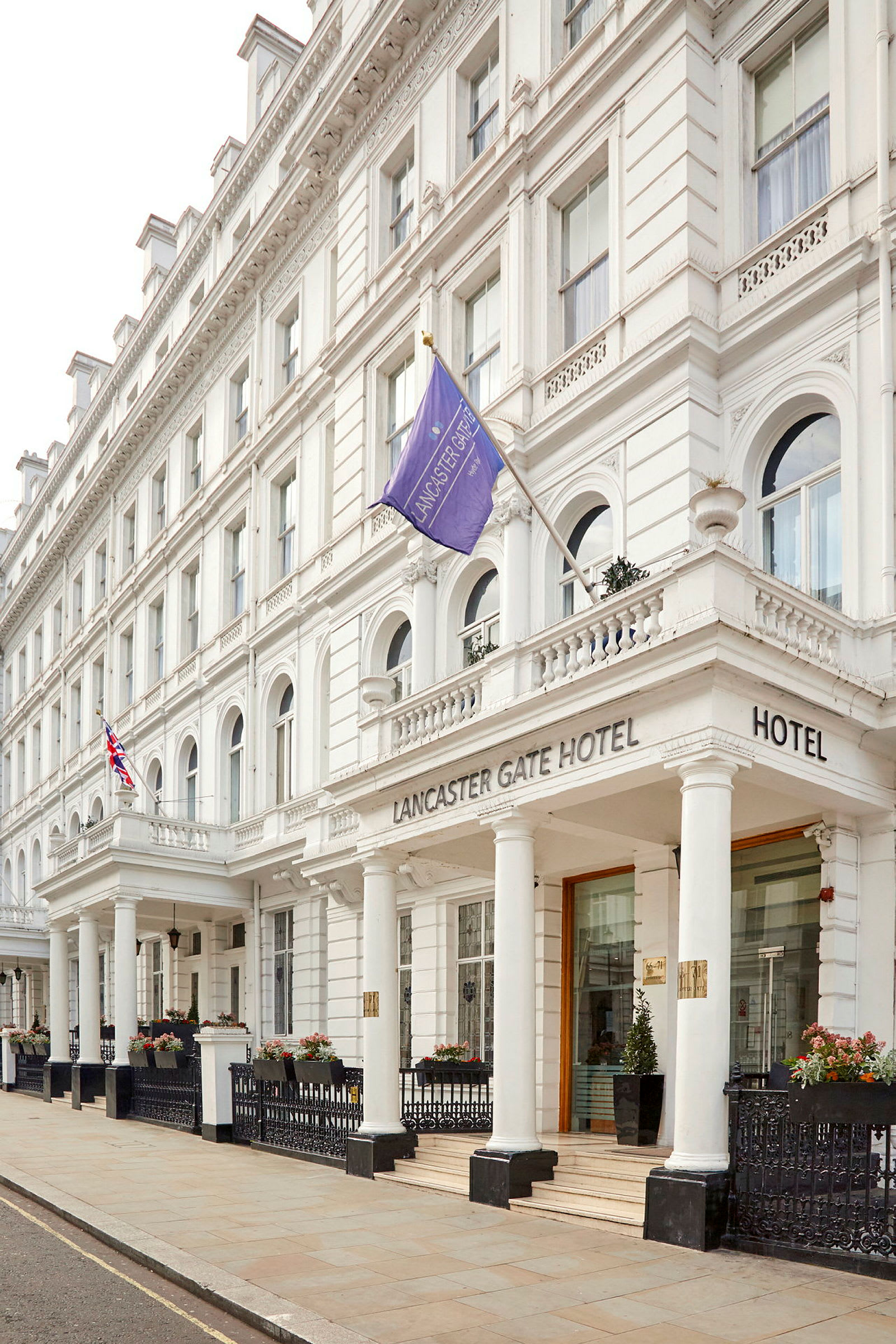 Lancaster Gate -hotelli kadulta katsottuna, valkoiset yksityiskohdat ja pylväät. (Tekoälyn luoma teksti)
