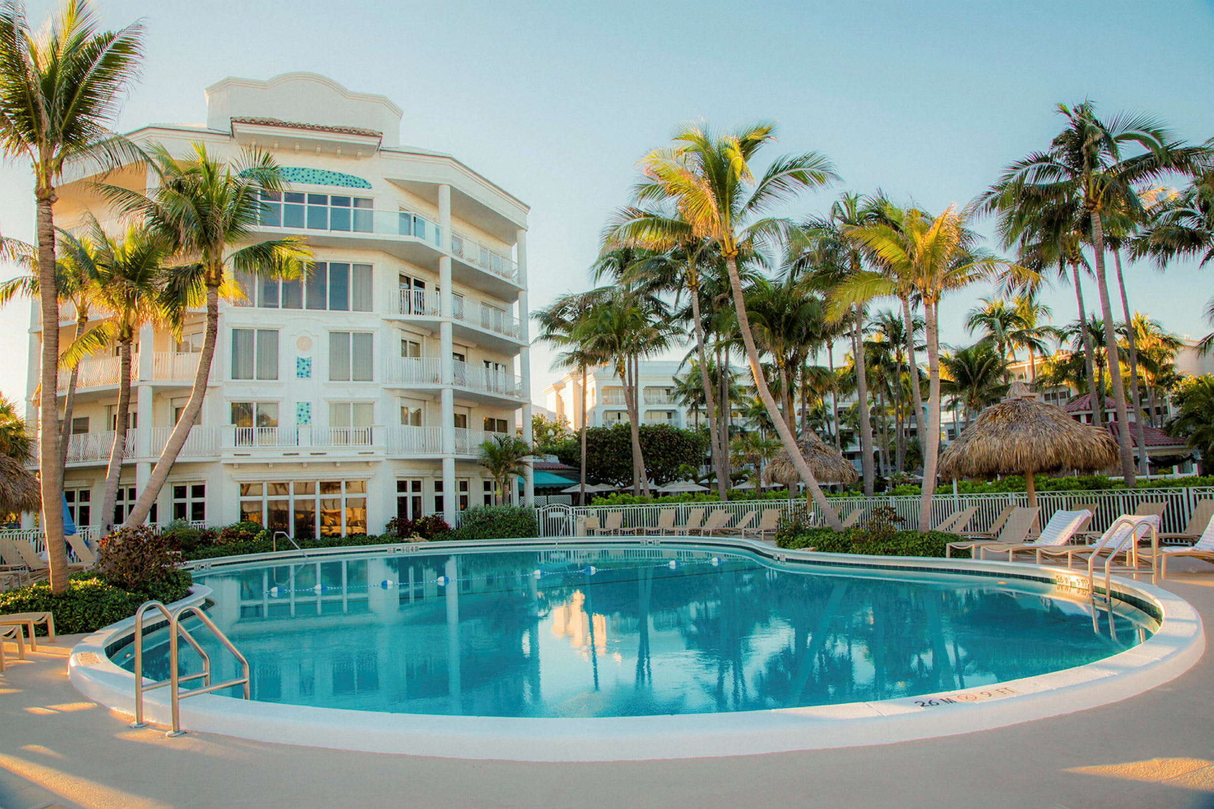 Hotellirakennus uima-altaan vieressä palmujen ympäröimänä. (Tekoälyn luoma teksti)