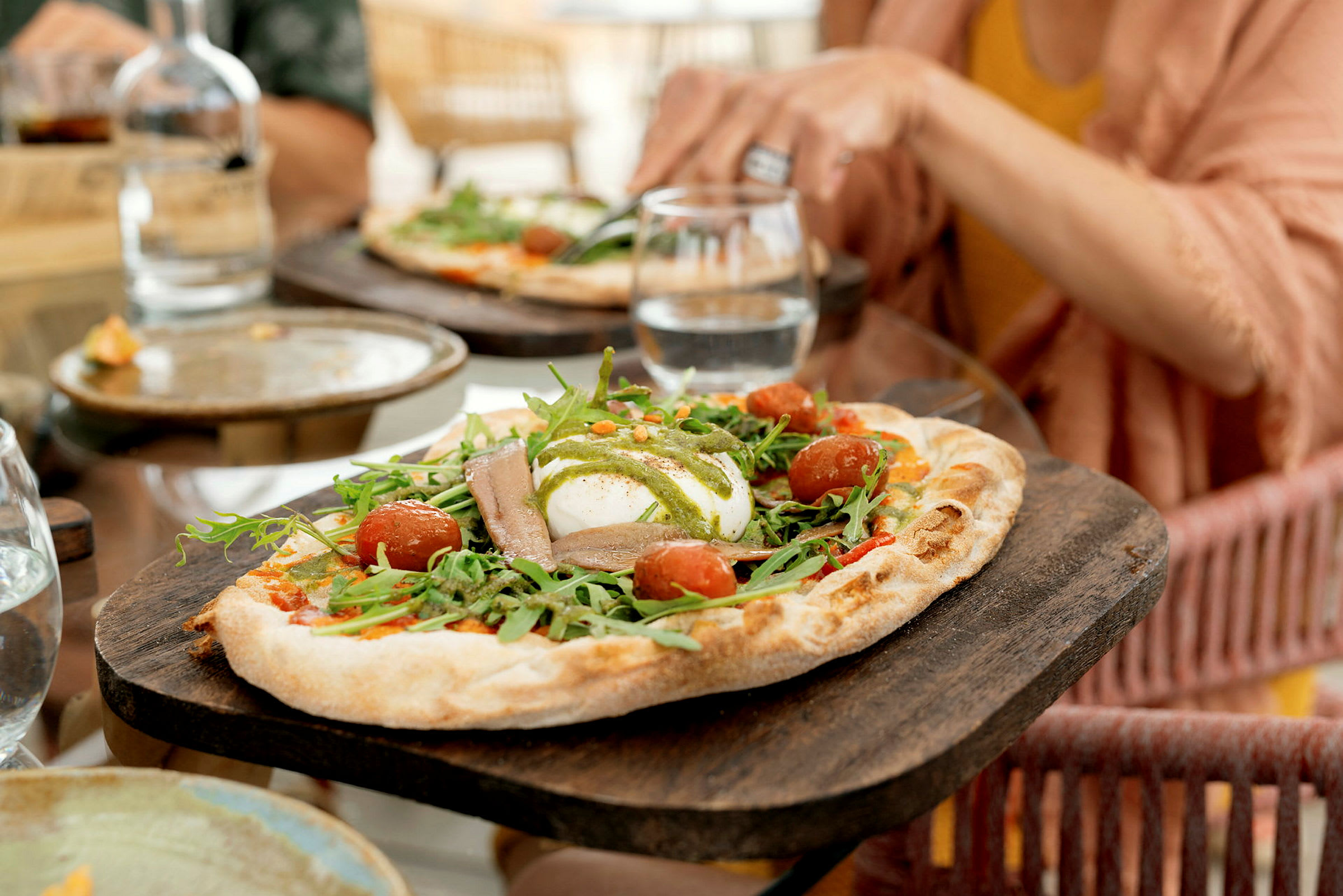 Lähikuva pizzasta, jossa on rucolaa, kirsikkatomaatteja ja mozzarellaa. (Tekoälyn luoma teksti)