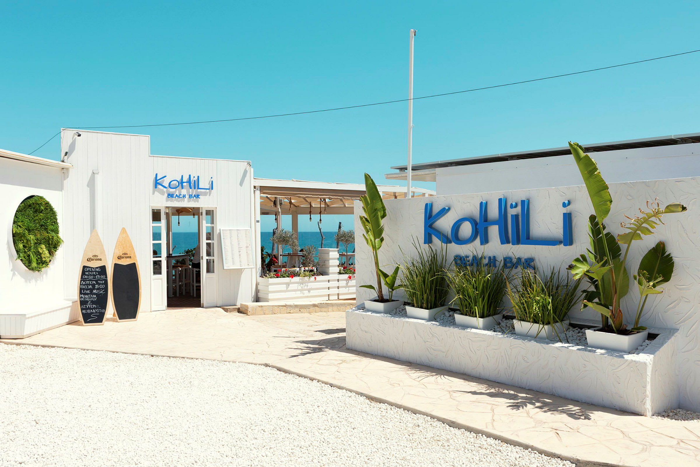 Kohili Beach Barin sisäänkäynti koristekasveineen ja kirkkaalla sinisellä taivaalla. (Tekoälyn luoma teksti)