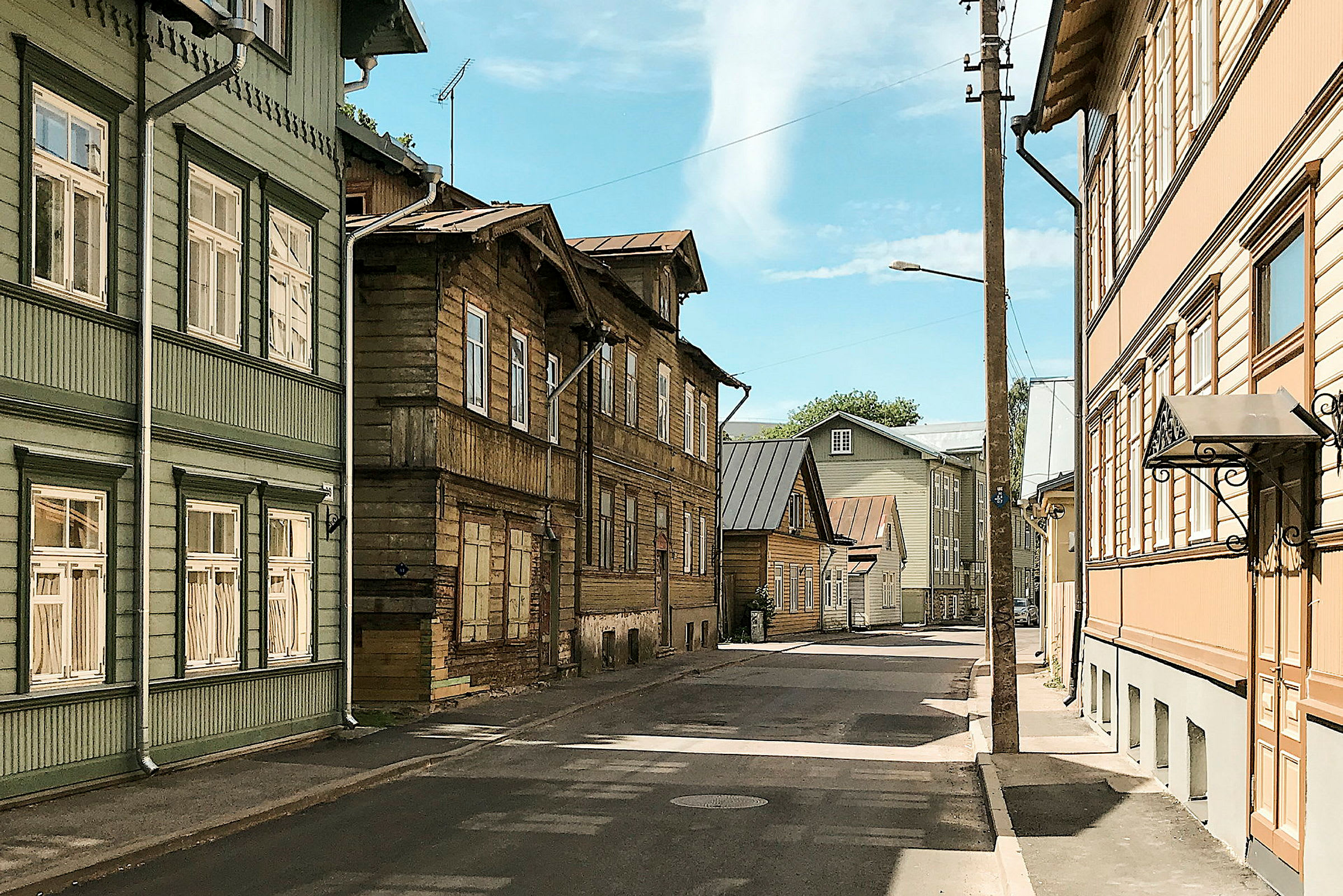 Katu, jota reunustavat eri väriset puutalot, taustalla näkyy sininen taivas. (Tekoälyn luoma teksti)