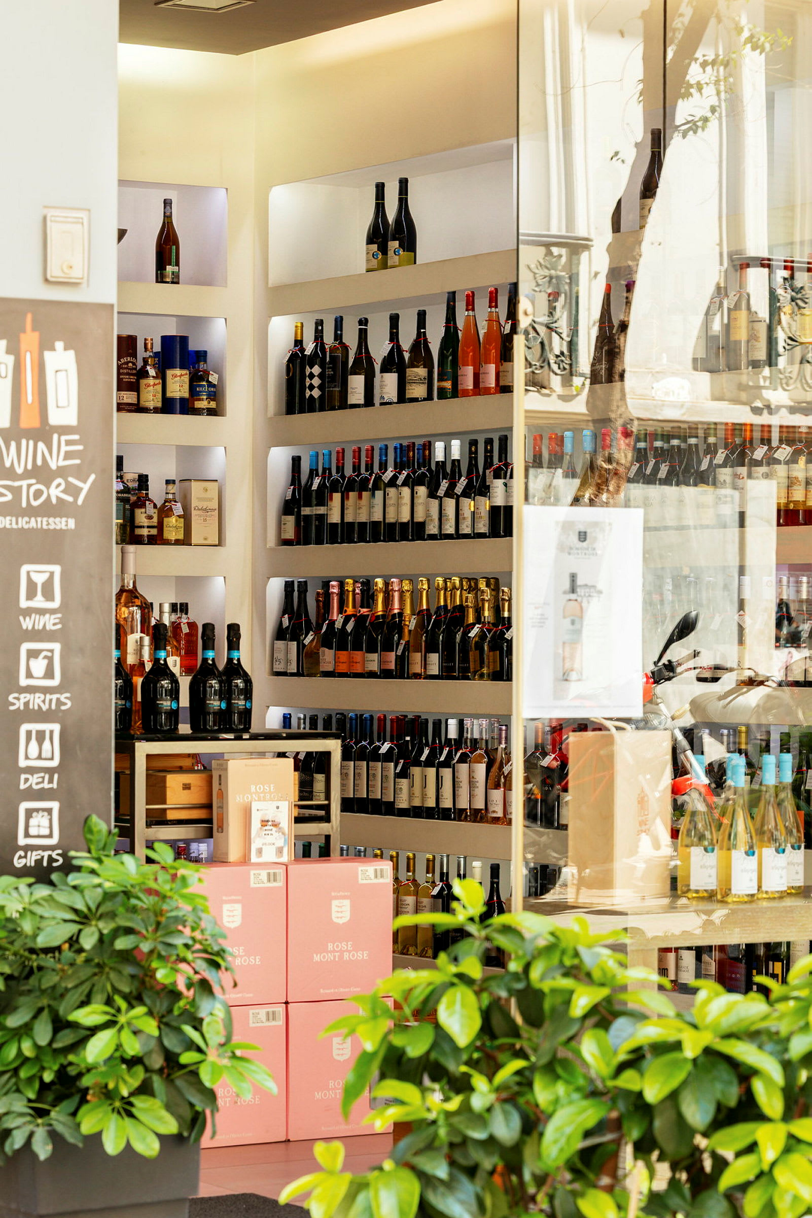 Viini- ja alkoholikauppa, jossa on hyllyillä pulloja sekä vaaleanpunaisilla etiketeillä varustettuja laatikoita. (Tekoälyn luoma teksti)