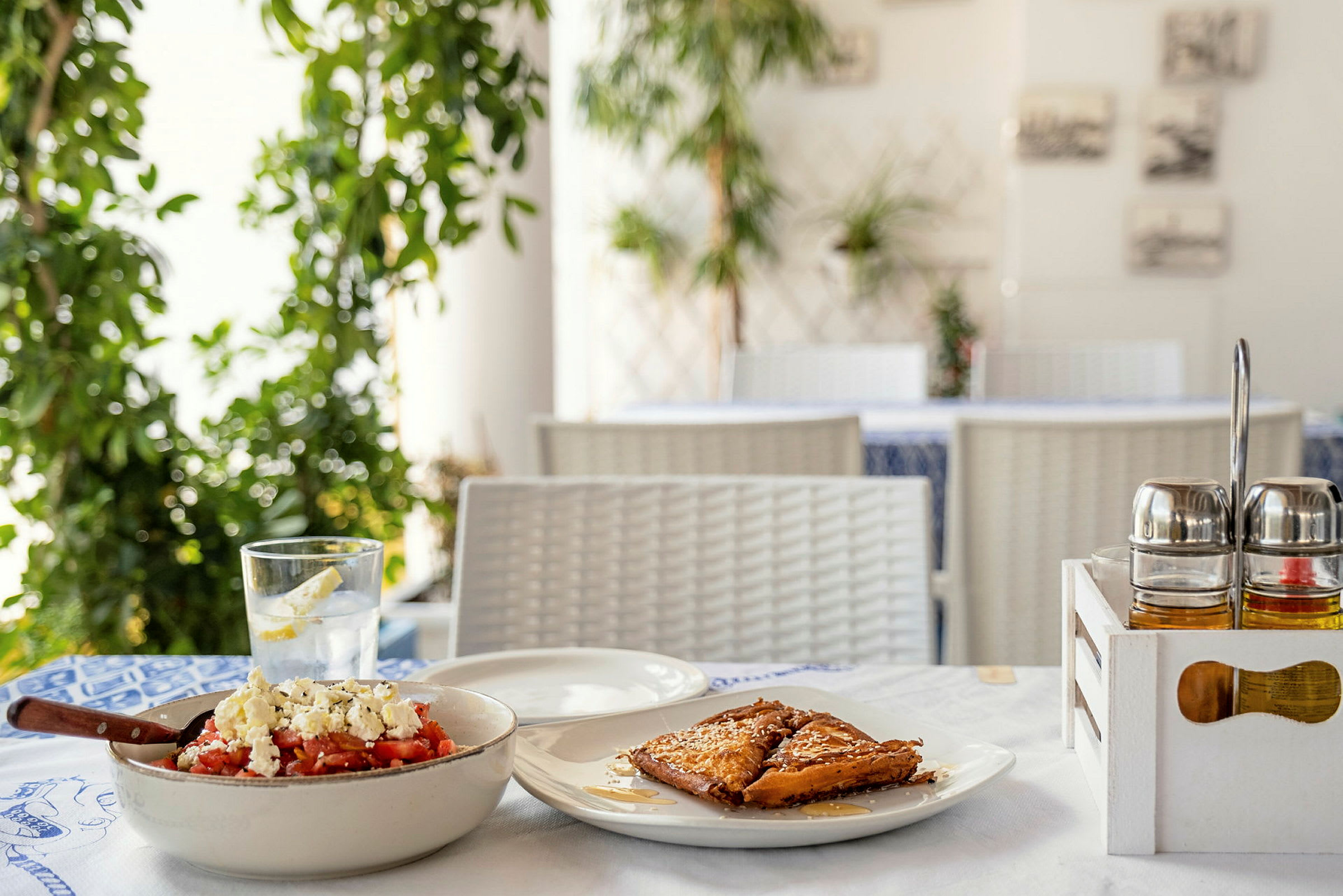 Lähikuva ravintolapöydästä, jossa on perinteinen kreikkalainen ruokalaji ja jälkiruoka. (Tekoälyn luoma teksti)