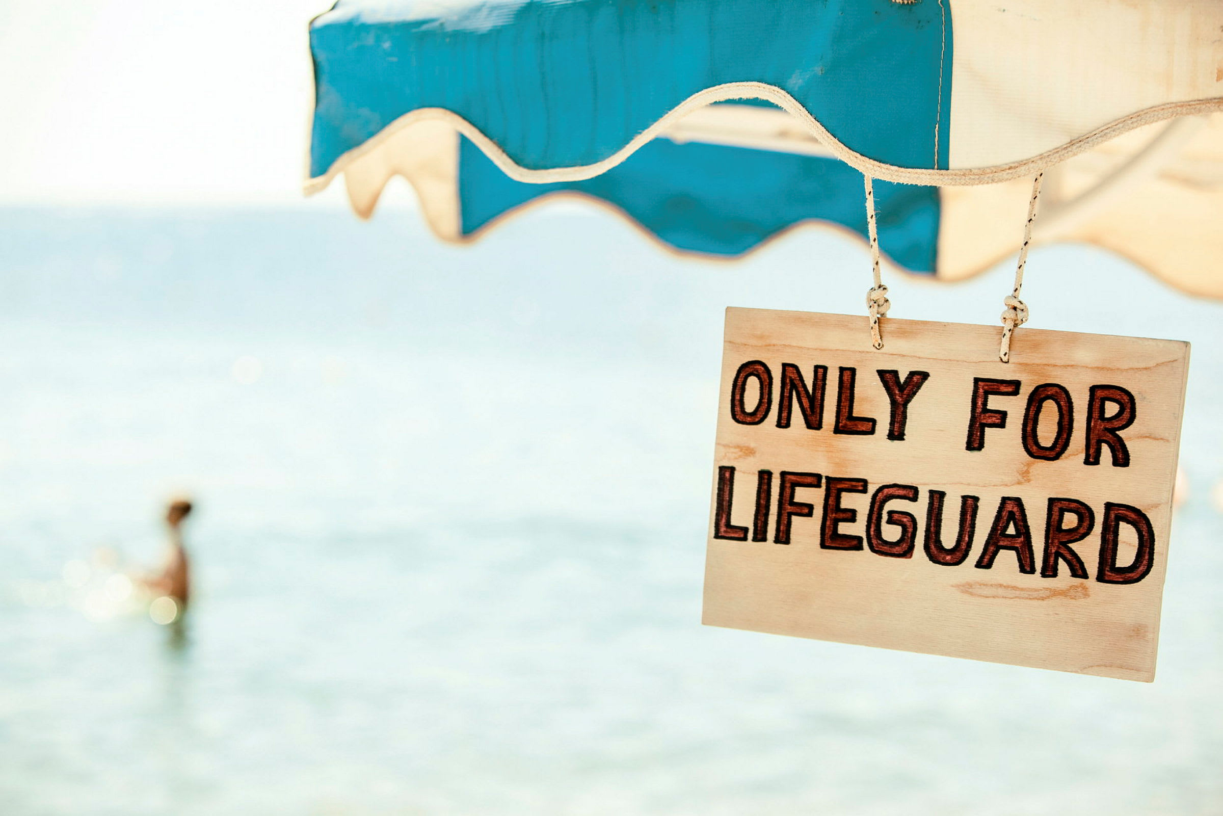 Kyltissä lukee 'Only for lifeguard' ja se on ripustettu aurinkovarjon alle lähellä merta. (Tekoälyn luoma teksti)