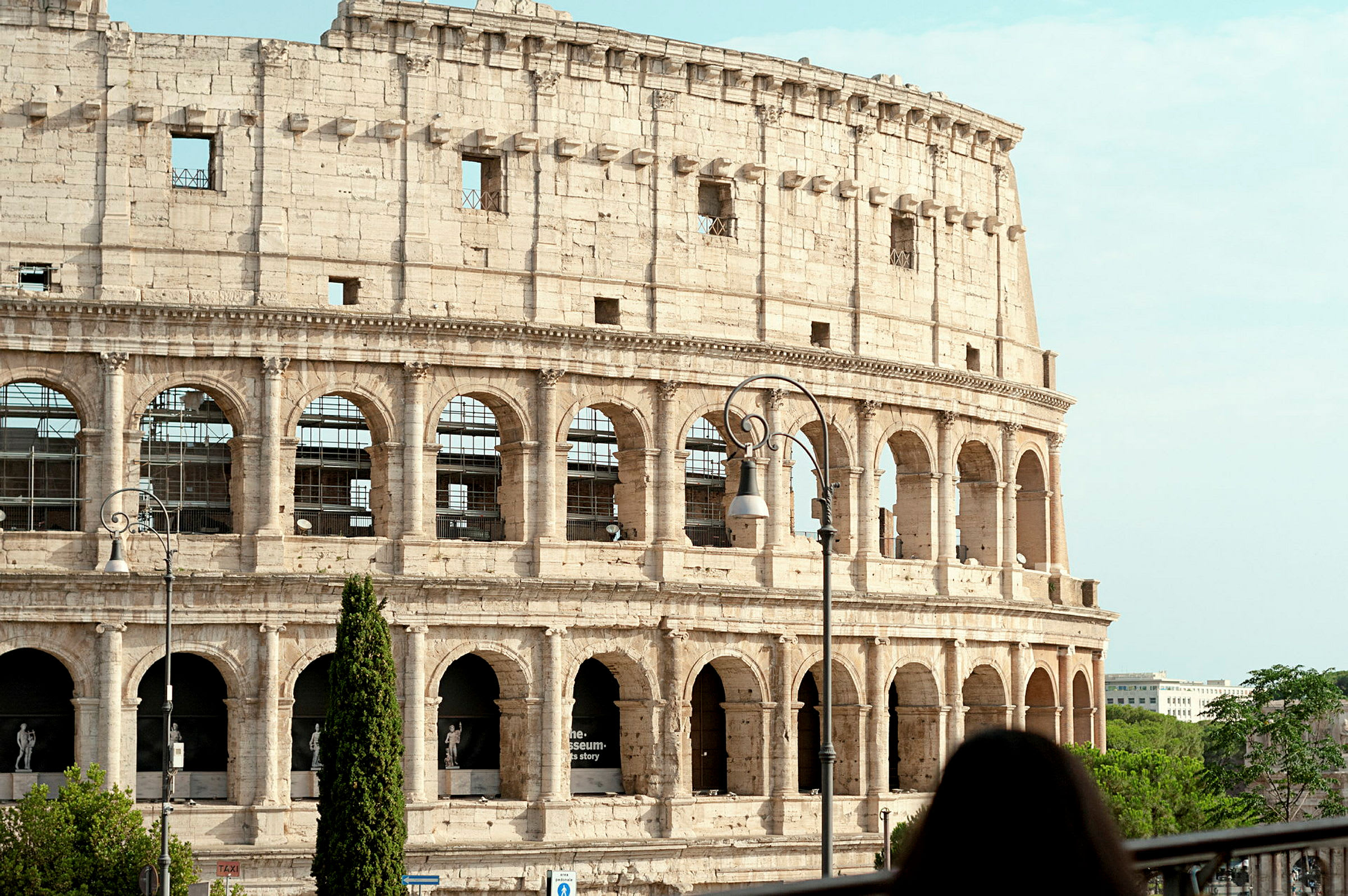 Kuva Rooman Colosseumista, Italiassa, etualalla oleva nainen. (Tekoälyn luoma teksti)