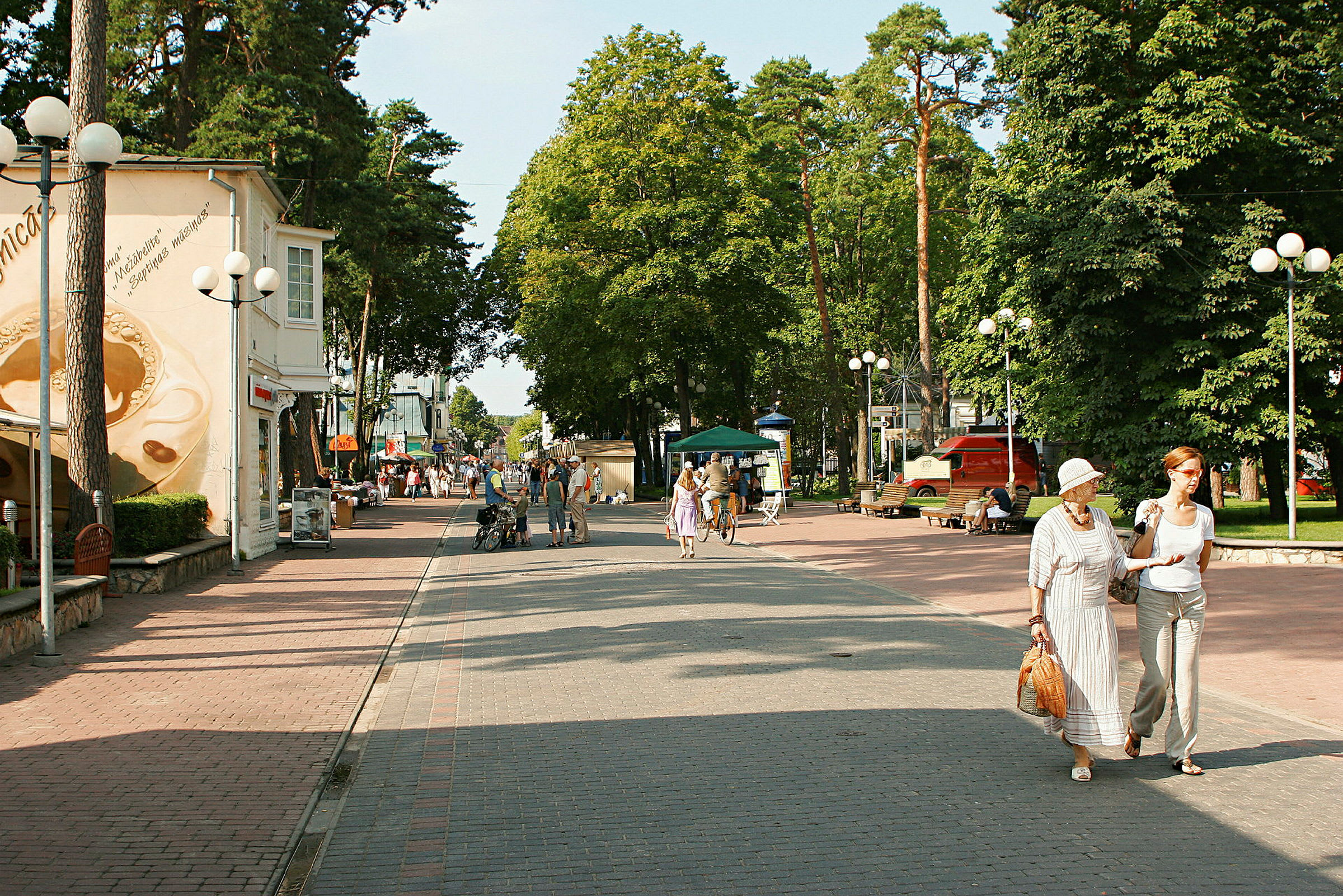 Kävelykatu, jossa ihmisiä, ympäröiviä rakennuksia, puita ja pysäköintialueita. (Tekoälyn luoma teksti)