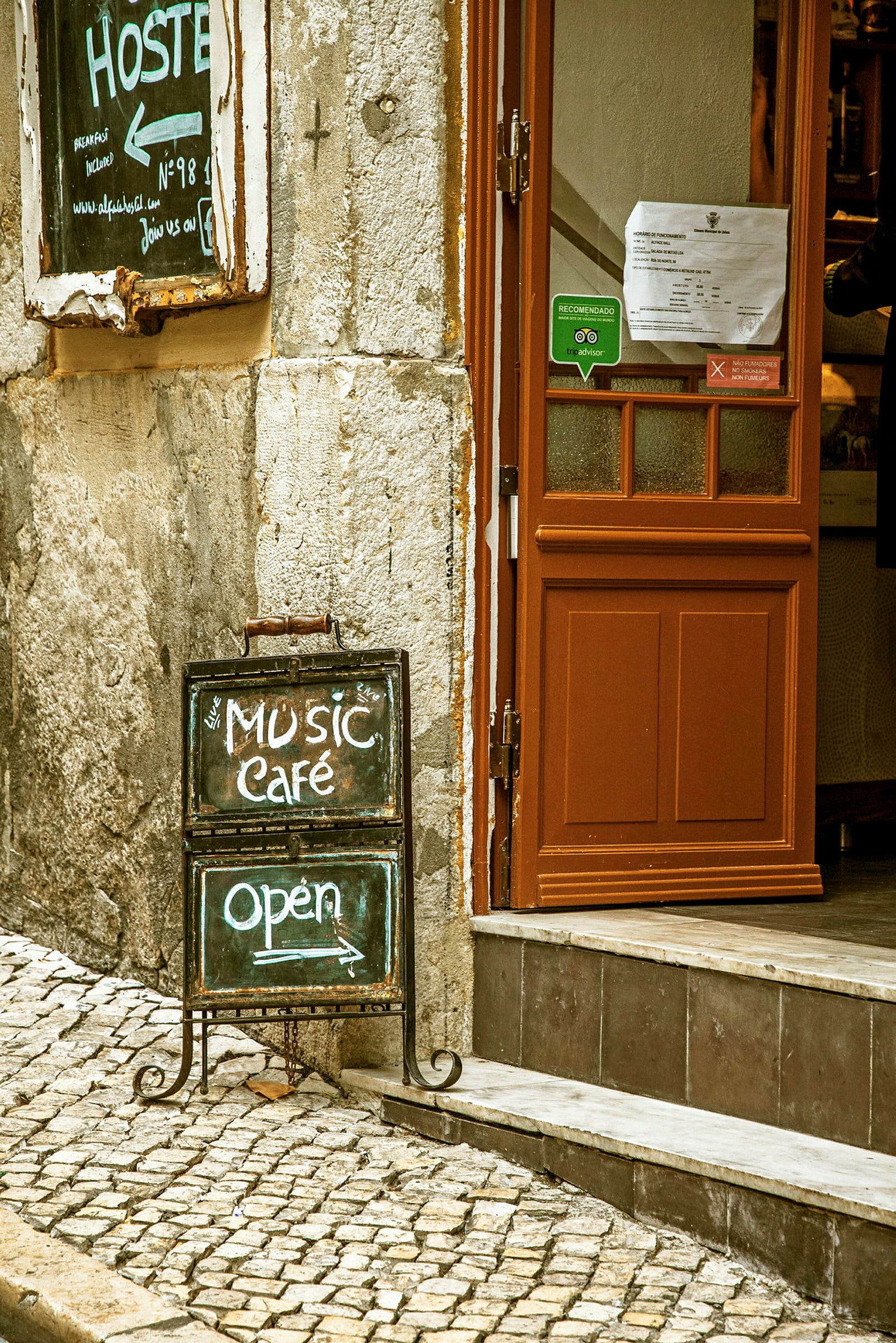 Kyltti kahvilan sisäänkäynnin edessä, jossa lukee "Music Café" ja "Open". (Tekoälyn luoma teksti)