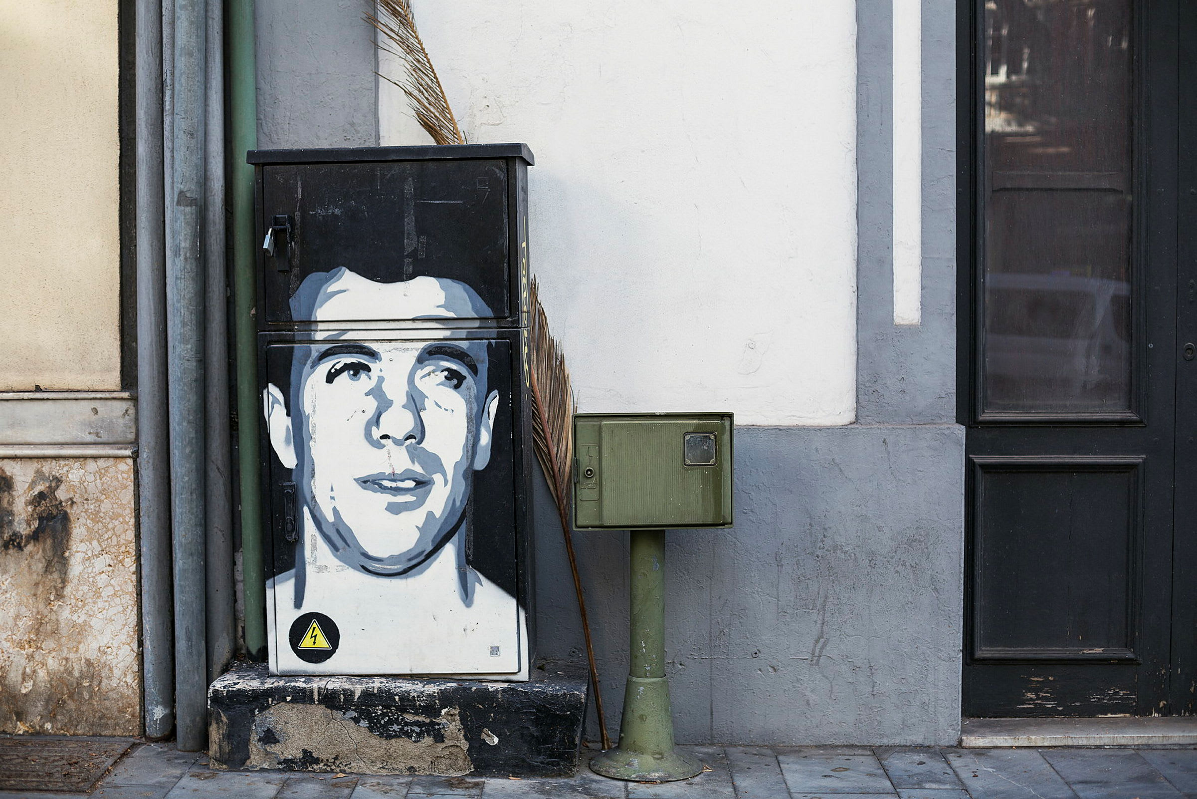 Graffitilla koristeltu sähkökaappi postilaatikkopilarin vieressä. (Tekoälyn luoma teksti)