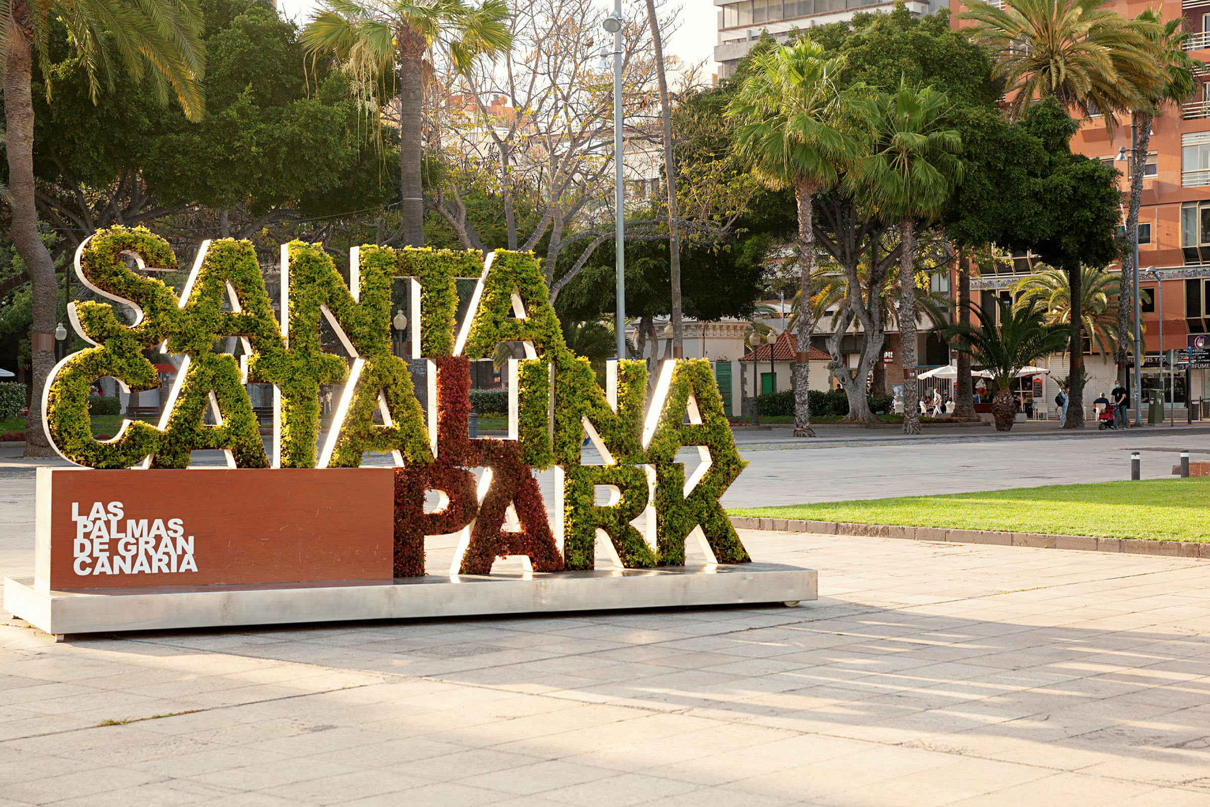 Kyltti, jossa lukee 'Santa Catalina Park', täynnä vihreää, ympäröitynä puilla kaupungin puistossa. (Tekoälyn luoma teksti)
