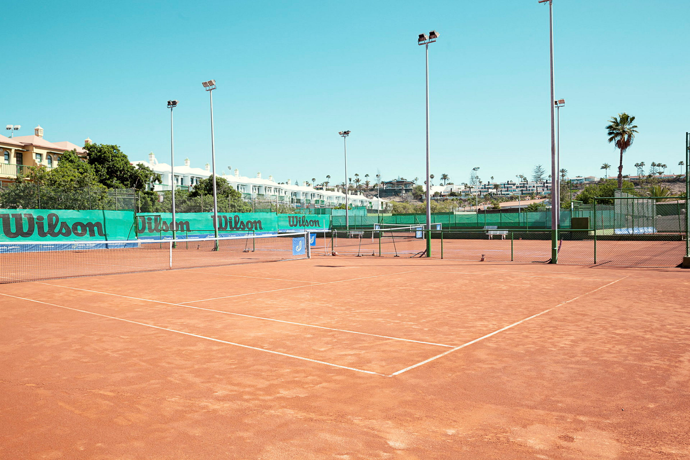 Tenniskentät hiekkapohjalla, ympäröity verkolla ja valaisinpylväillä. (Tekoälyn luoma teksti)