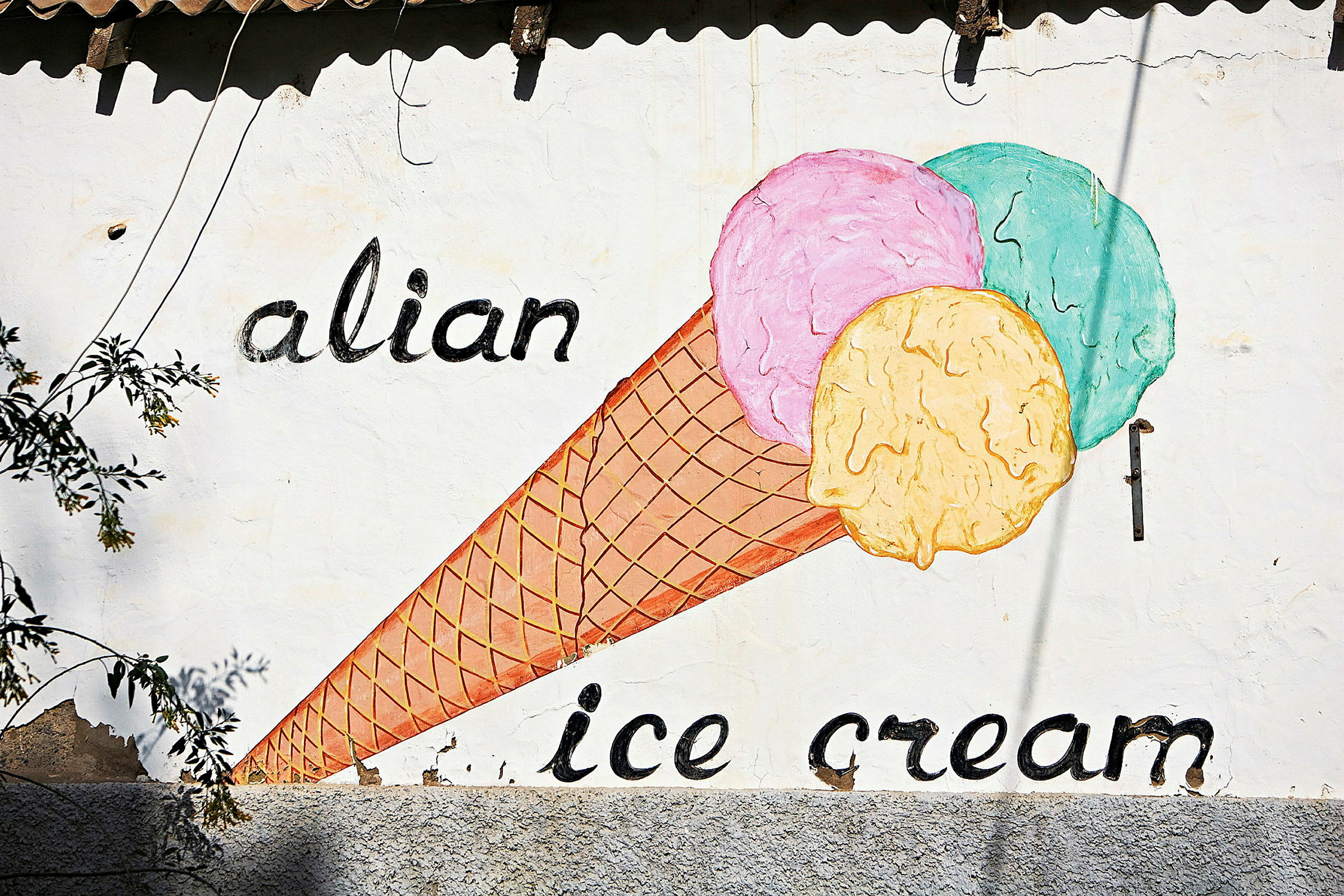 Maalaus jäätelötötteröstä, jossa on kolme värikästä palloa seinällä, jossa lukee 'alian ice cream'. (Tekoälyn luoma teksti)