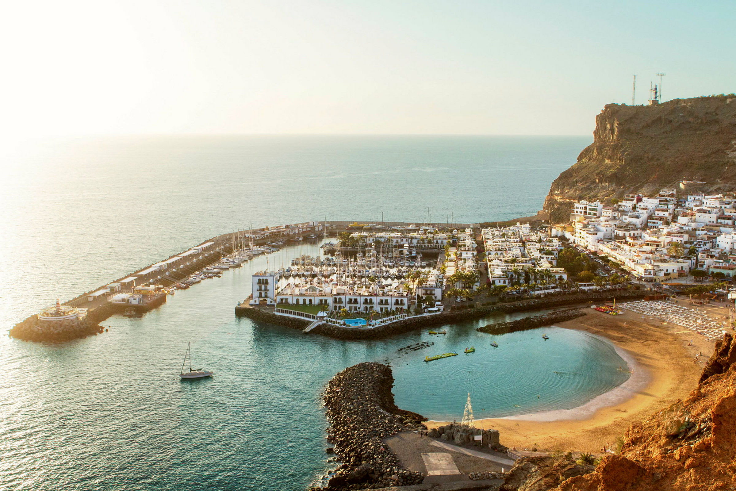 Rannikolla sijaitseva kaupunki, jossa on venevenesatama, valkoisia rakennuksia ja kallioiden ympäröimä ranta. (Tekoälyn luoma teksti)