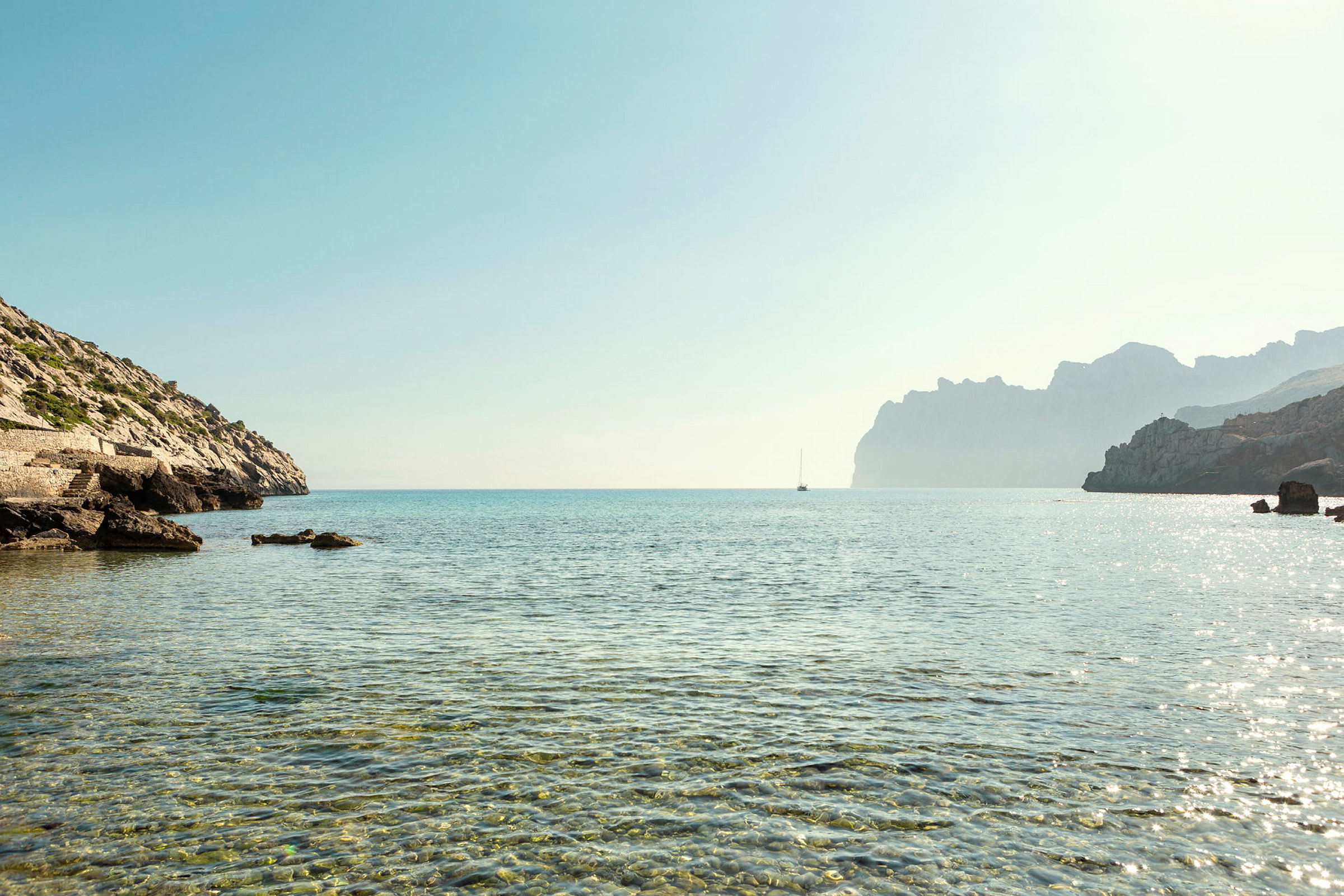 Selkeä merinäkymä, jossa kivinen rantaviiva ja vene kaukaisuudessa. (Tekoälyn luoma teksti)