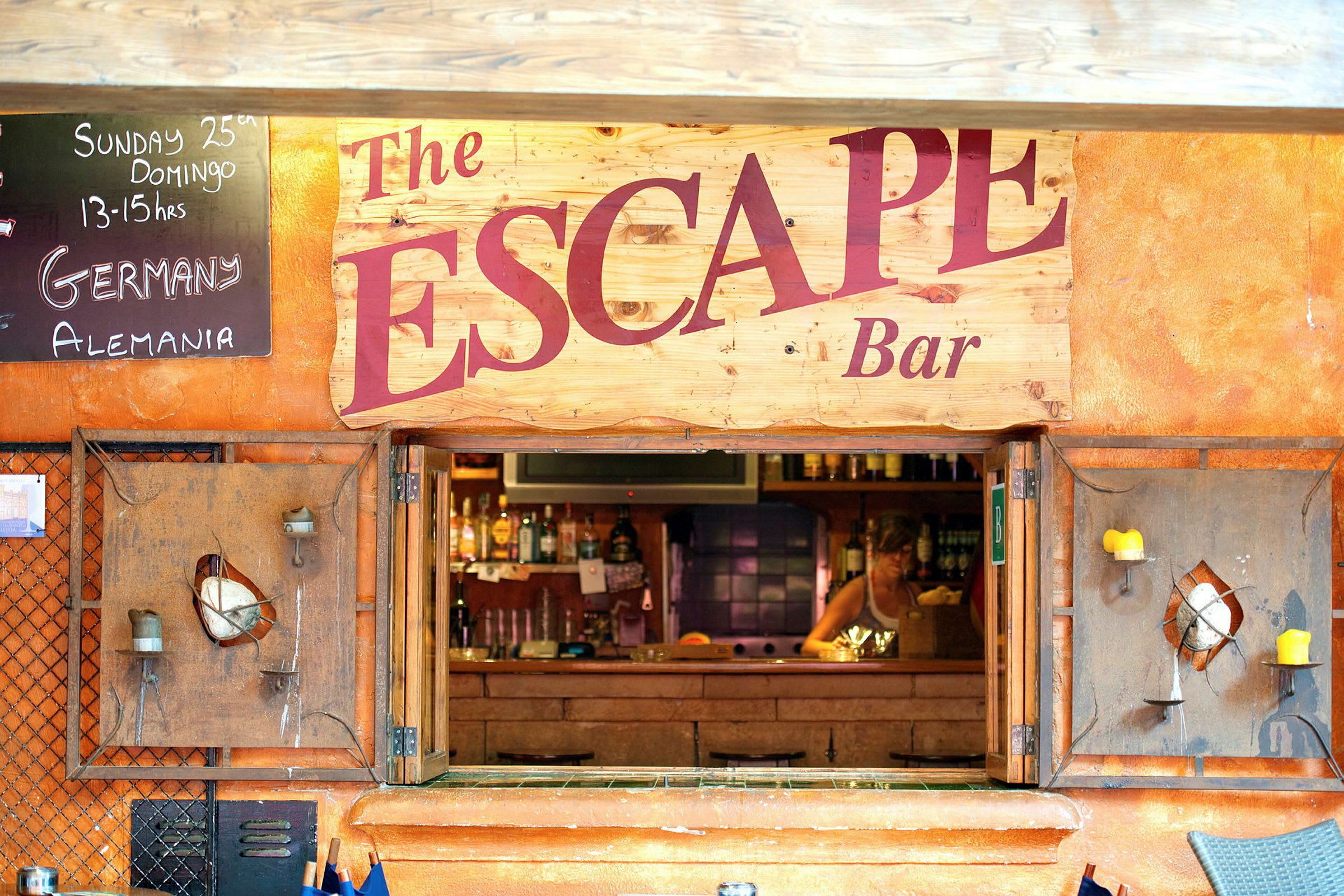 Baari, jonka nimi on 'The Escape', näkyy. Sisältää kyltin tekstillä ja aukon baariin. (Tekoälyn luoma teksti)