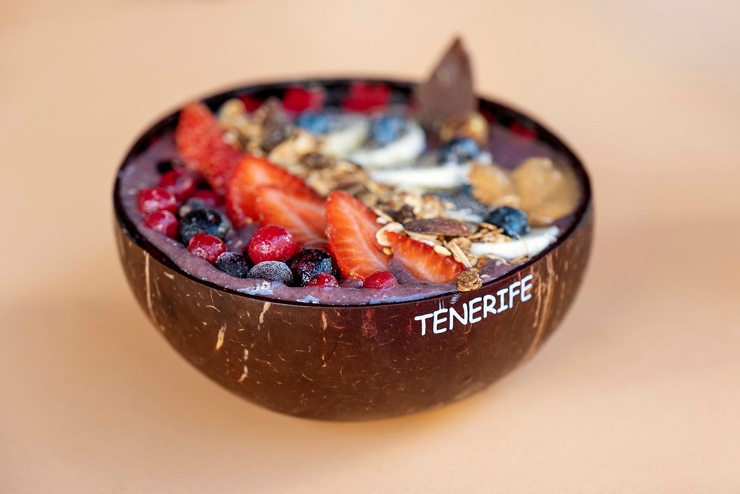 Acai-kulho, jossa marjoja ja granolaa, tarjoiltuna kookospähkinäkupissa. (Tekoälyn luoma teksti)