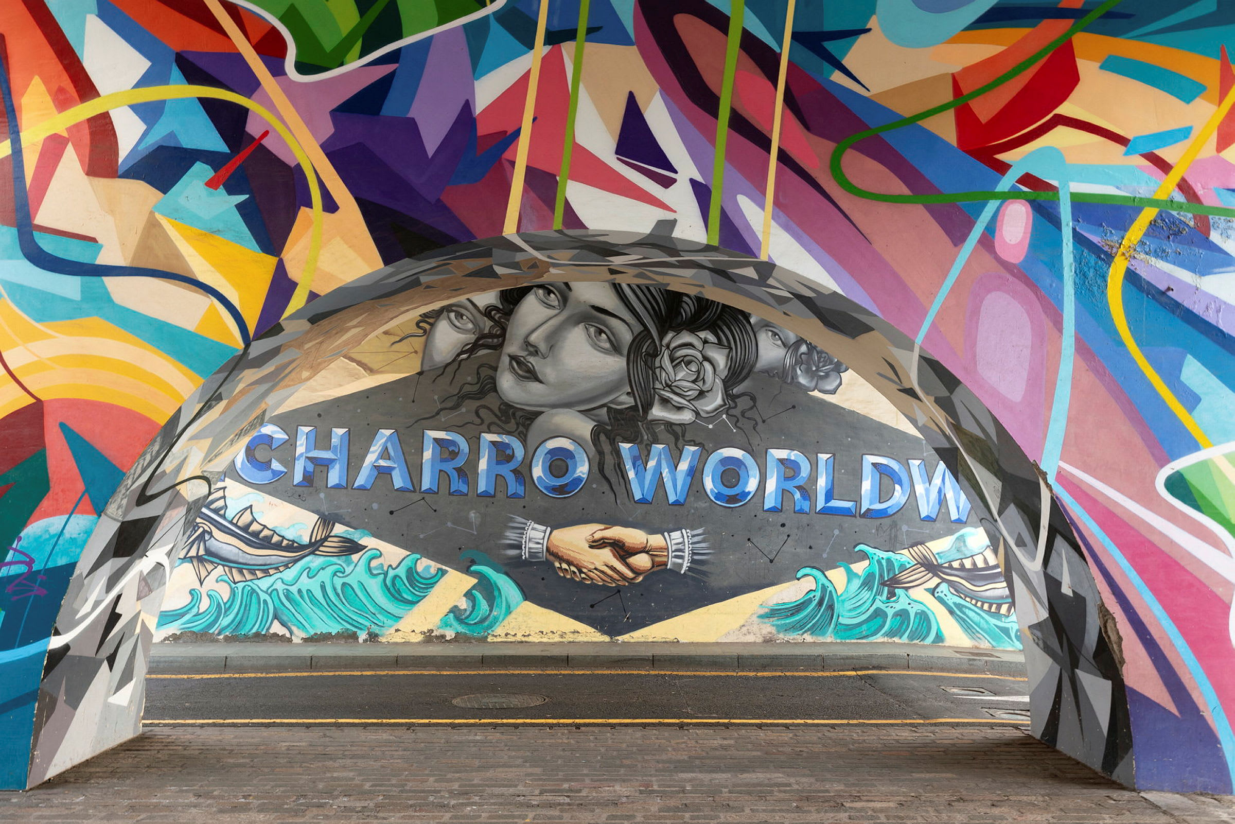 Värikäs seinämaalaus, jossa lukee 'Charro World', kädenpuristus ja rannikkoteema. (Tekoälyn luoma teksti)