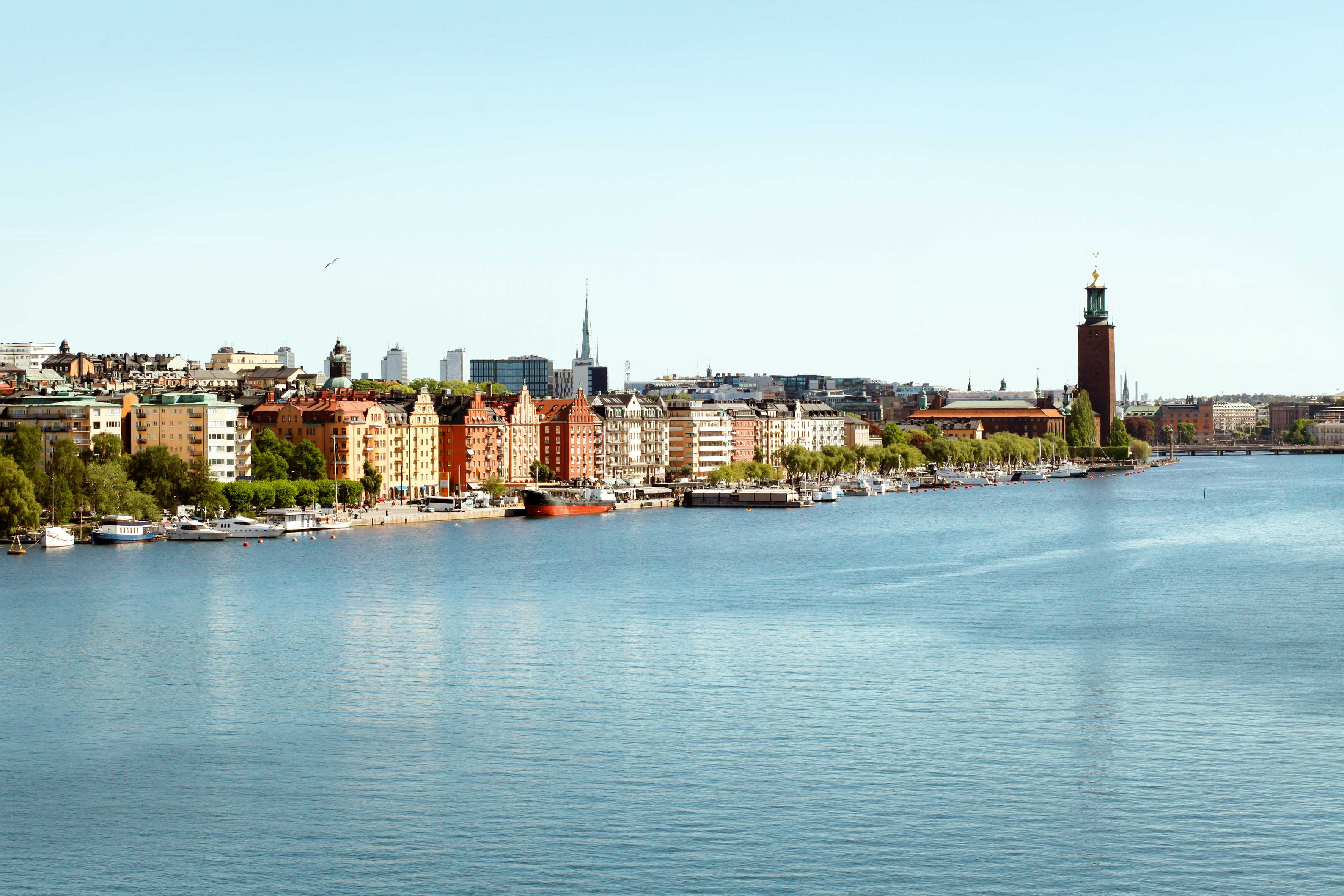 Kaupunkimaisema vesielementin vieressä, etualalla rakennuksia ja veneitä. (Tekoälyn luoma teksti)