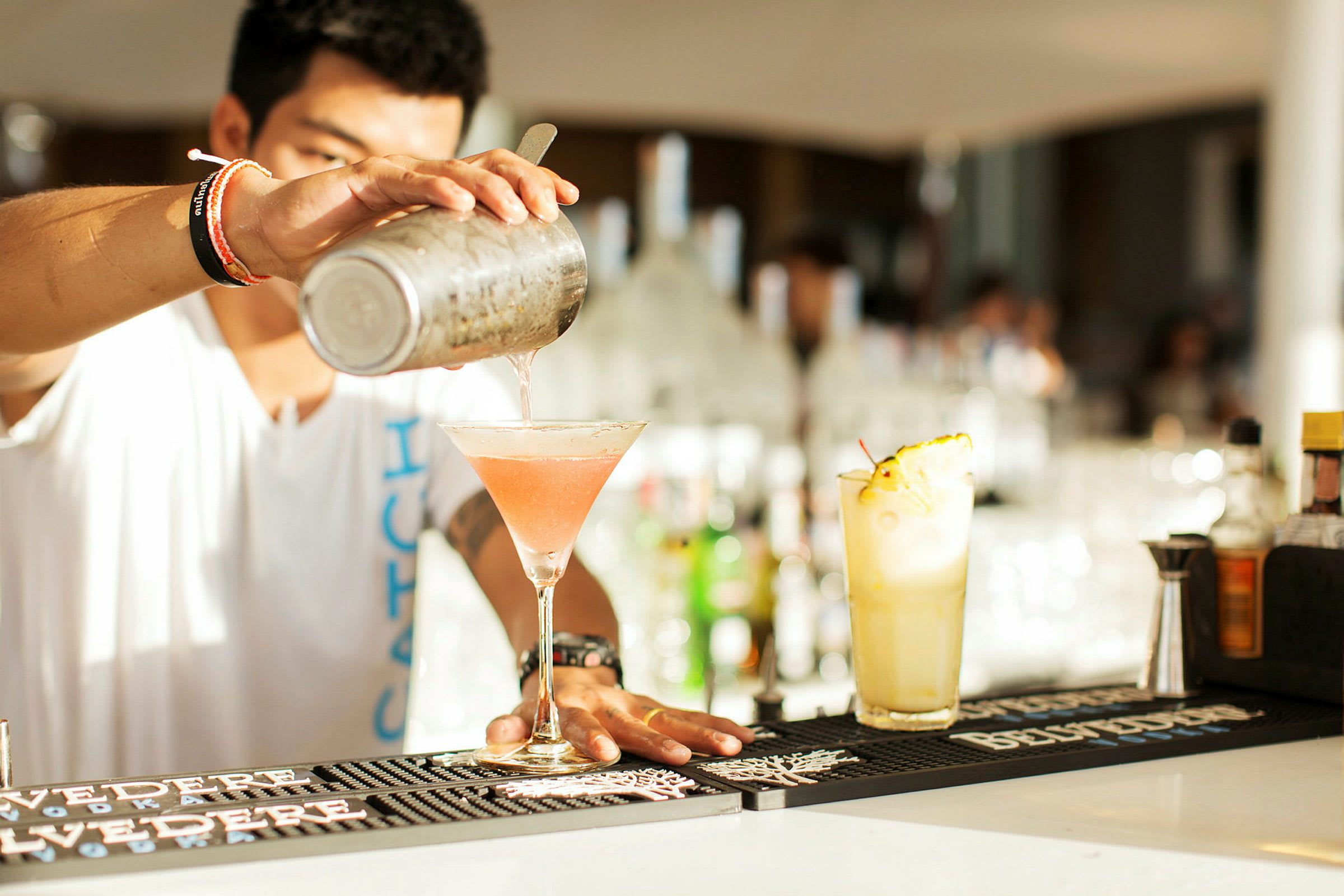 Cocktailin sekoittaminen ja kaataminen lasiin baaritiskillä. (Tekoälyn luoma teksti)