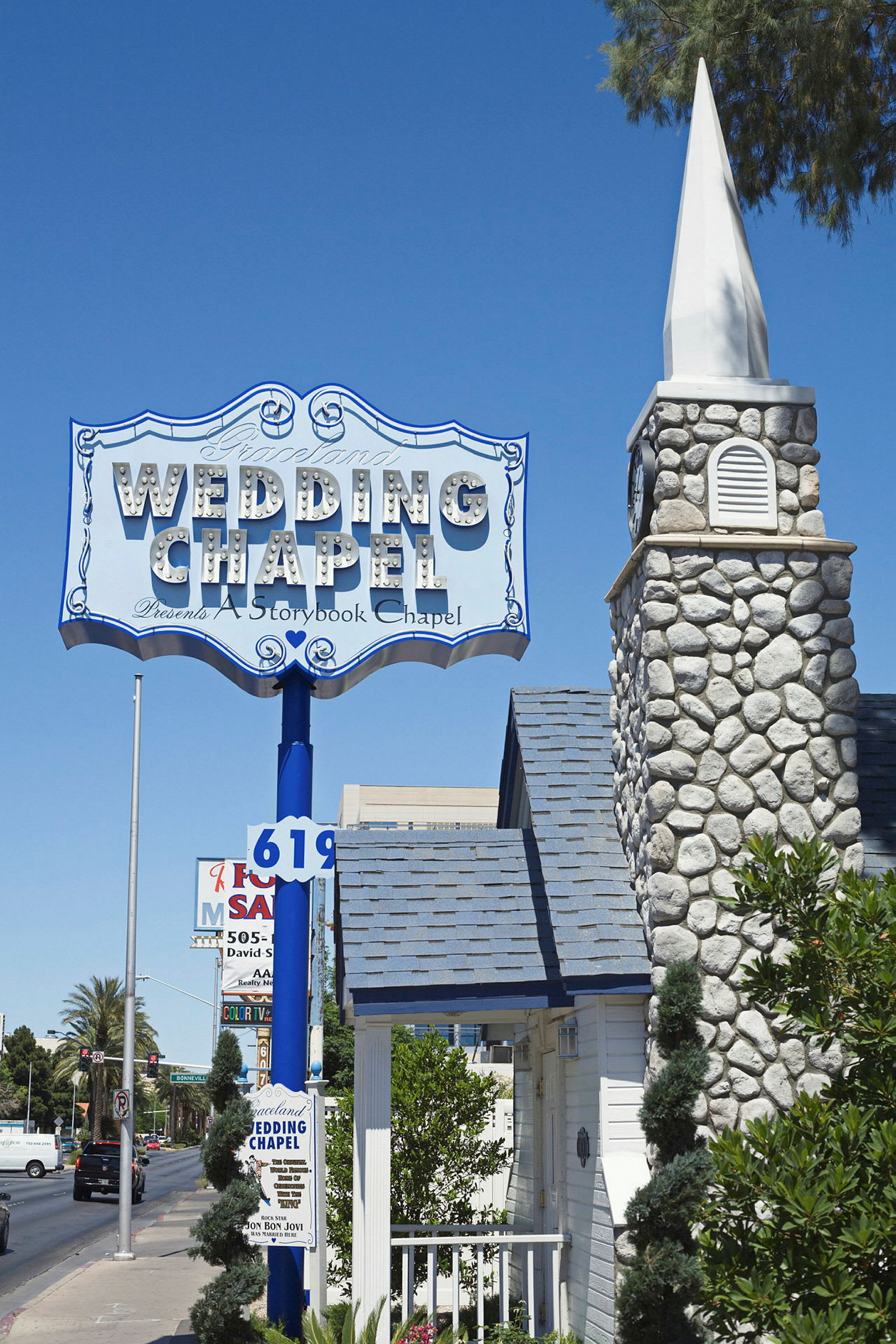 Kyltti, jossa lukee 'Wedding Chapel', kivikirkon rakennuksen yläpuolella, taustalla sininen taivas. (Tekoälyn luoma teksti)