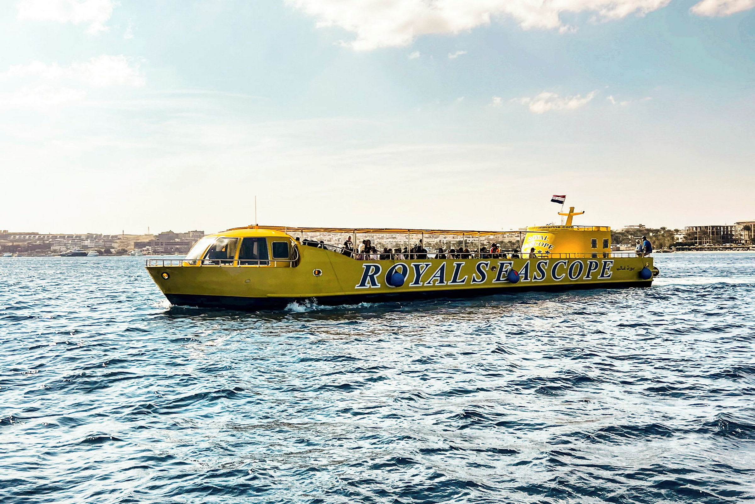 Keltaisen sightseeing-veneen kyljessä lukee 'ROYALS SEA SCOPE' ja se näkyy vedellä. (Tekoälyn luoma teksti)