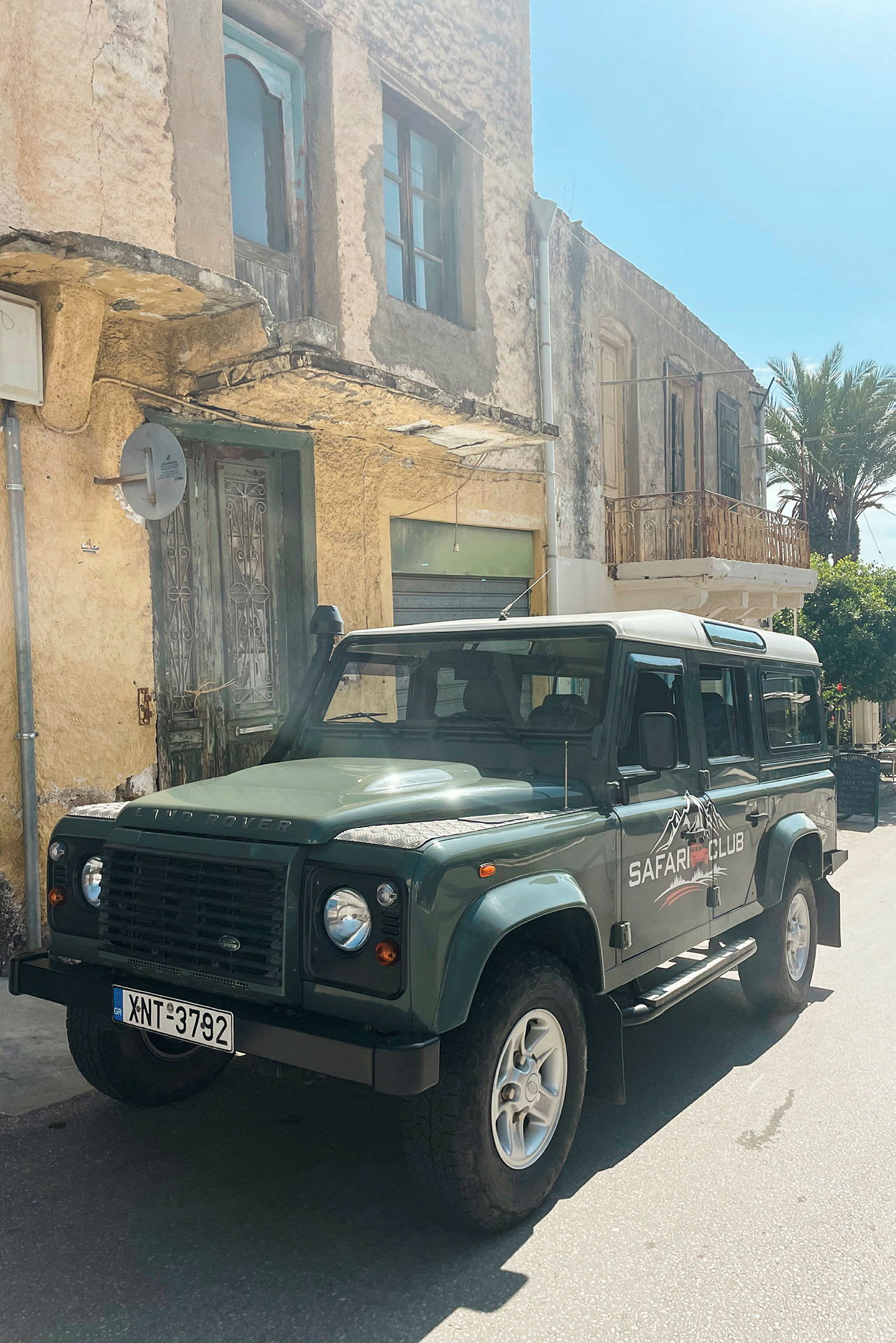 Safari-klubin auto on pysäköity vanhan rakennuksen eteen, jossa on kuluneet julkisivut ja rustiikkiset ovet. (Tekoälyn luoma teksti)