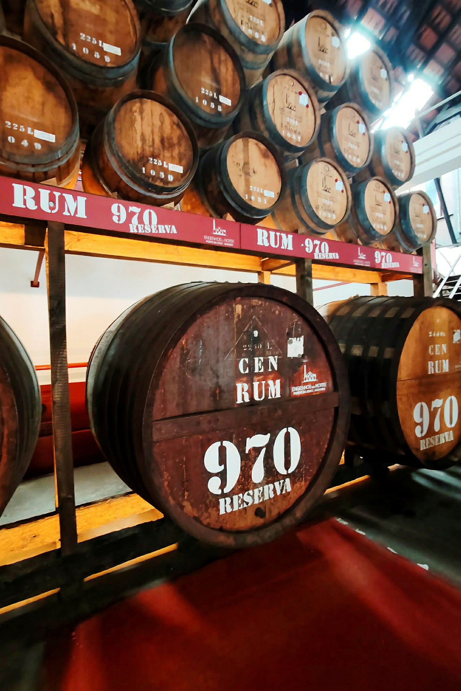 Useita suuria puutynnyreitä säilytyshyllyllä, merkitty tekstillä 'Rum 970 Reserva'. (Tekoälyn luoma teksti)