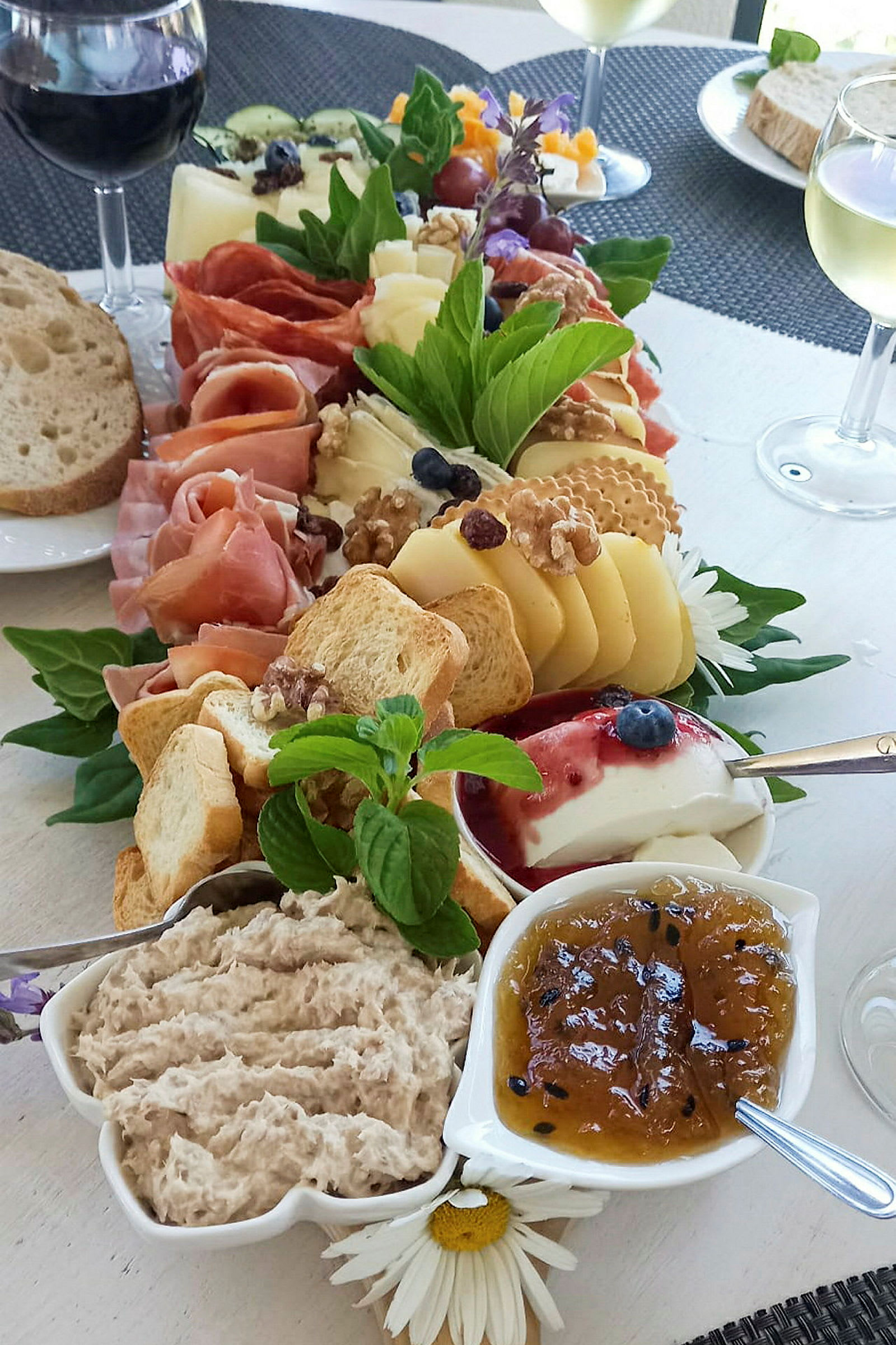 Tarjoilu, joka sisältää juustoa, kinkkua, leipää ja lisukkeita kuten hilloa ja tahnaa. (Tekoälyn luoma teksti)