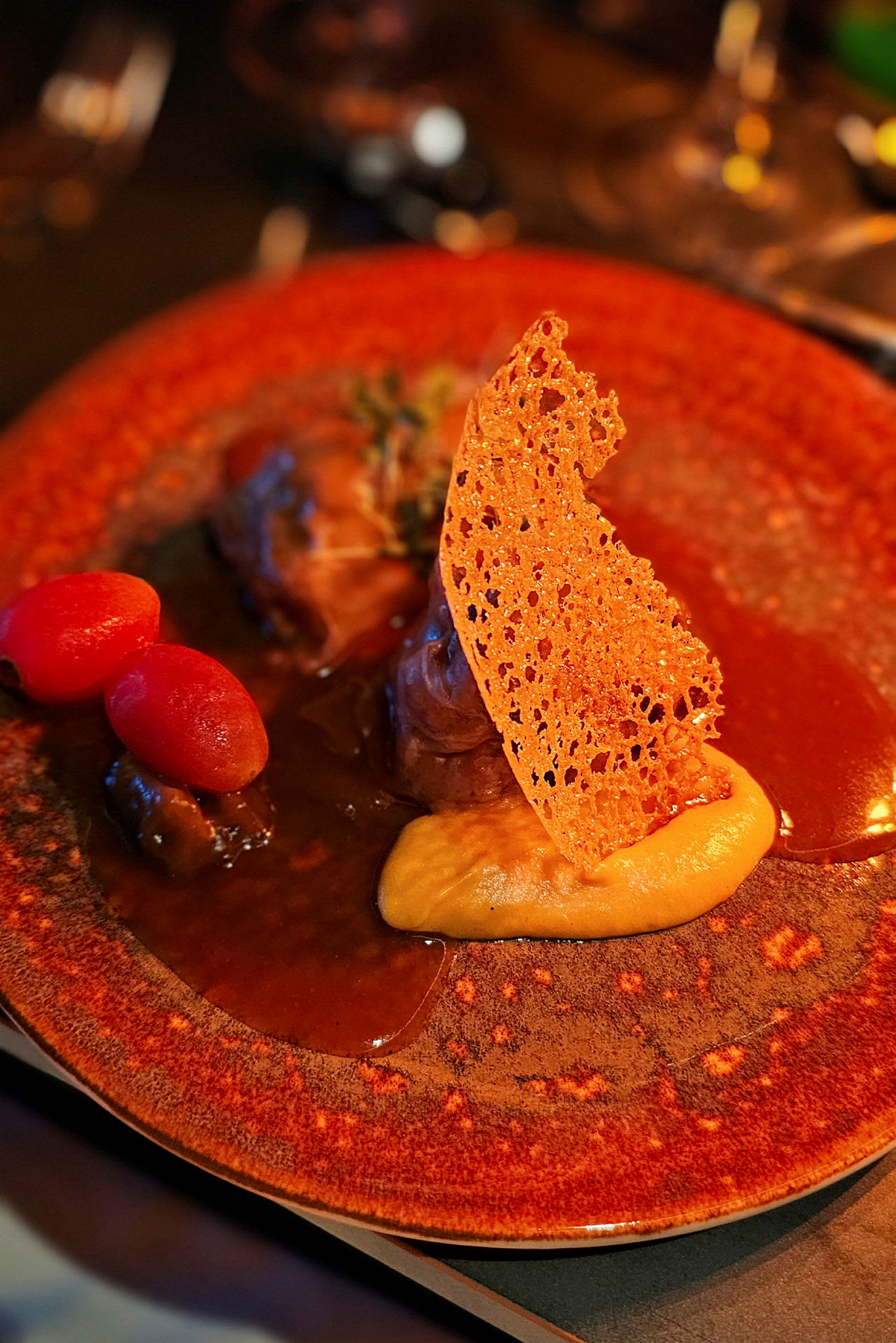 Lautanen, jossa on gourmetateria koostuen kastikkeesta, soseesta, rapeasta koristeosasta ja pienistä tomaateista. (Tekoälyn luoma teksti)