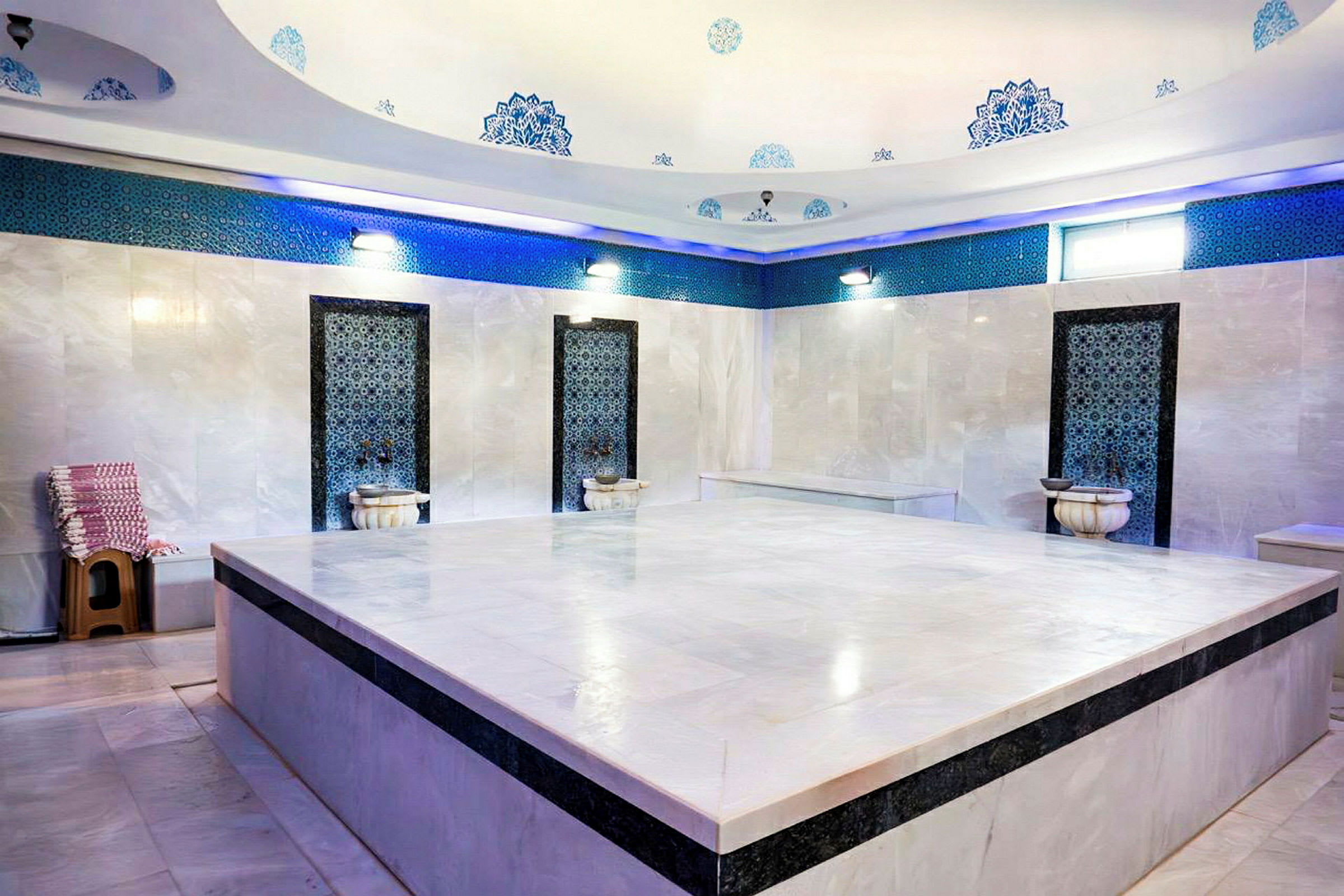 Perinteinen turkkilainen hamam, jossa on marmoriseinät, koristeellisia yksityiskohtia ja suuri keskialusta. (Tekoälyn luoma teksti)