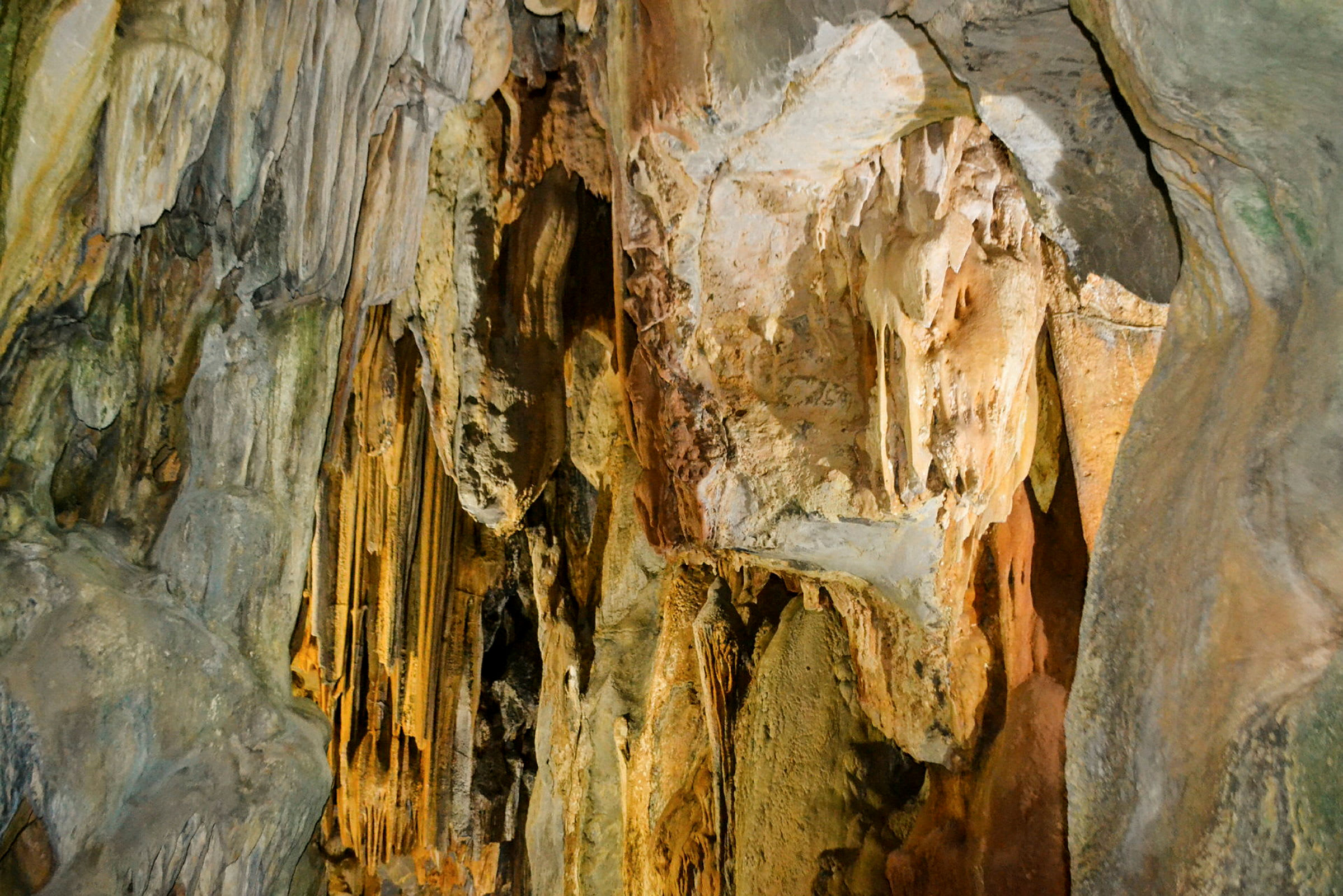 Kuva luolasta, jossa on stalaktiitteja ja stalagmiitteja seinillä. (Tekoälyn luoma teksti)
